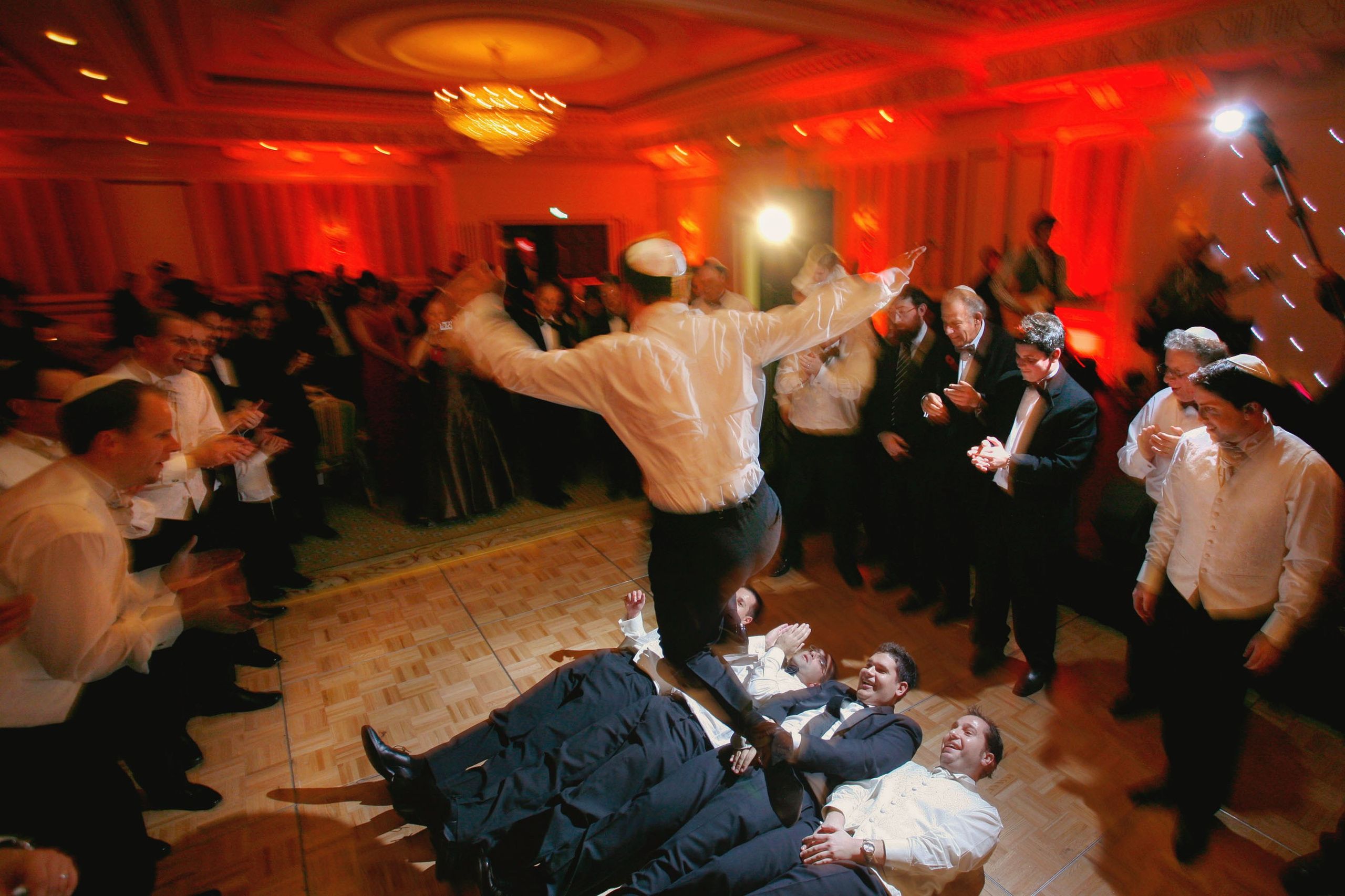 Jewish man jumping over men during wedding celebration at Ritz-Carlton Powerscourt, Ireland.