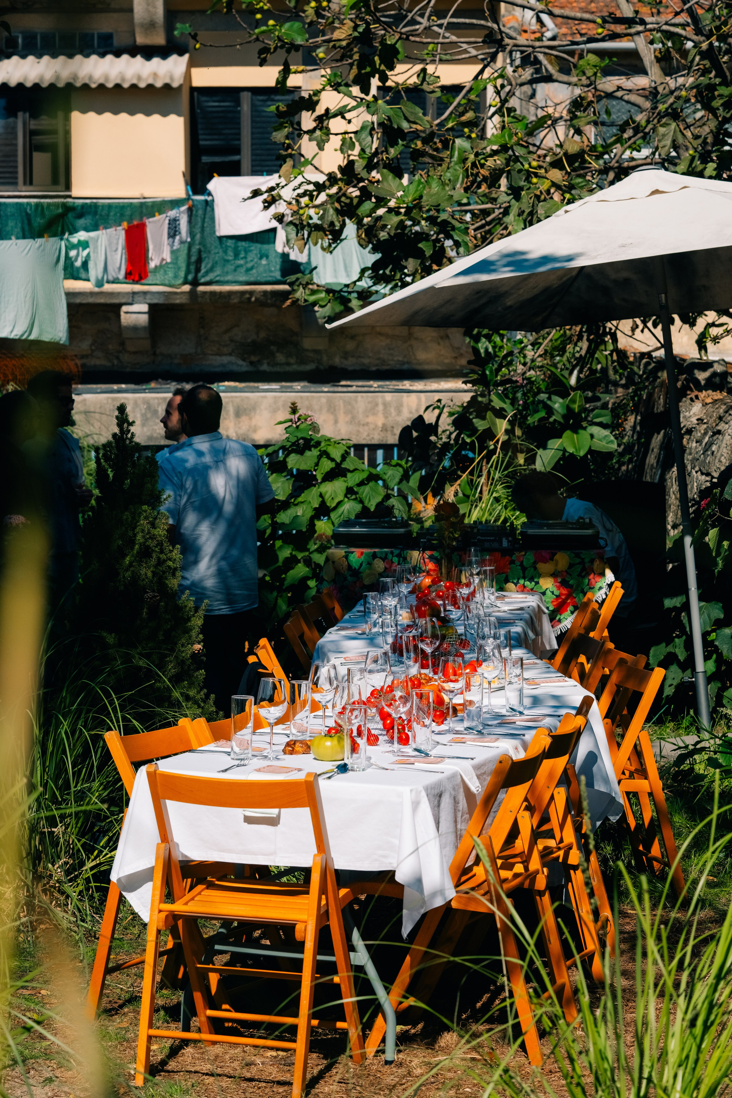 Conjunto de mesa de jantar ao ar livre comprido para uma reunião no jardim. Mesa de jantar comprida ao ar livre lindamente decorada com copos e decoração floral para uma festa ou reunião no jardim.