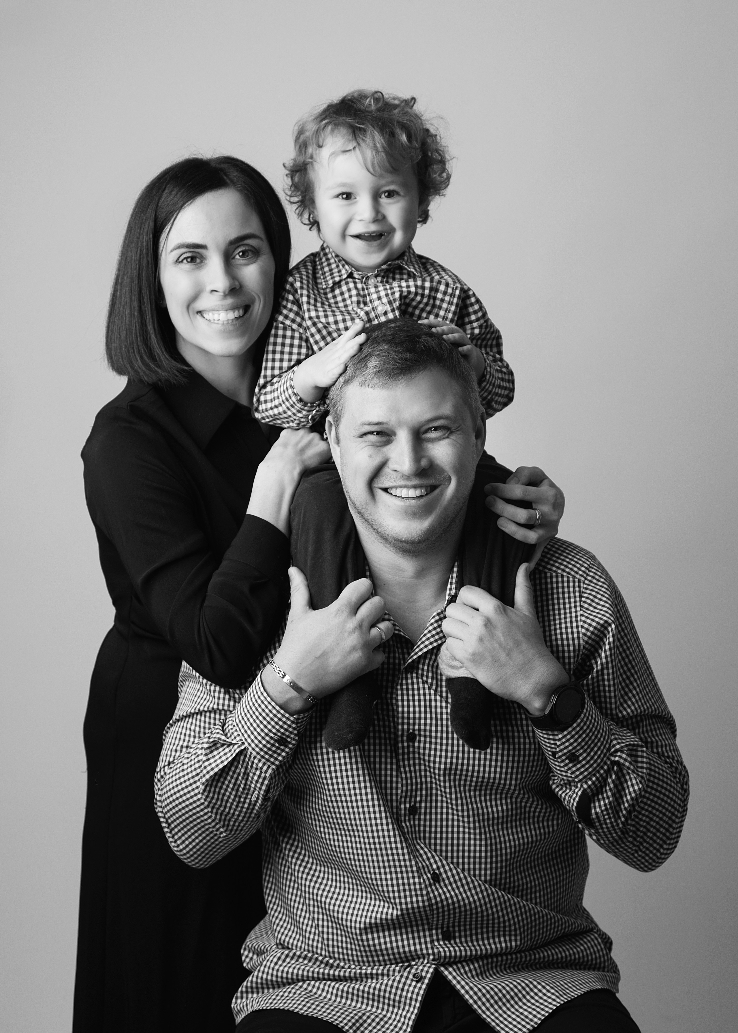 Familjefotografering i studion fångar ögonblicket av lycka med barn, mamma och pappa tillsammans.
