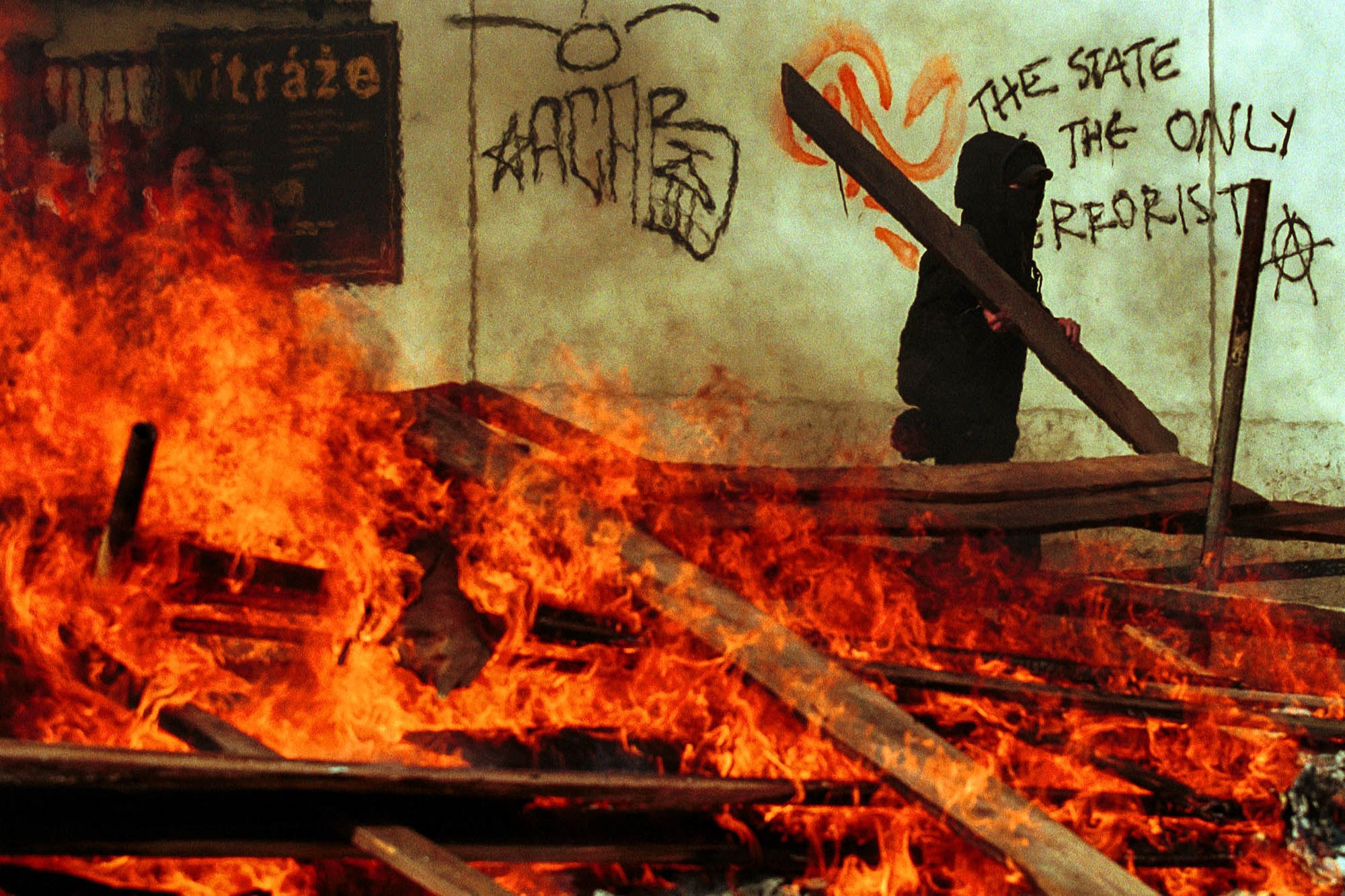 An anti IMF/World Bank protestor helps to build a burning road block in the Nusle neighborhood of Prague on September 27, 2000 after mass rioting broke out causing the annual meeting to end early amid due to security concerns.