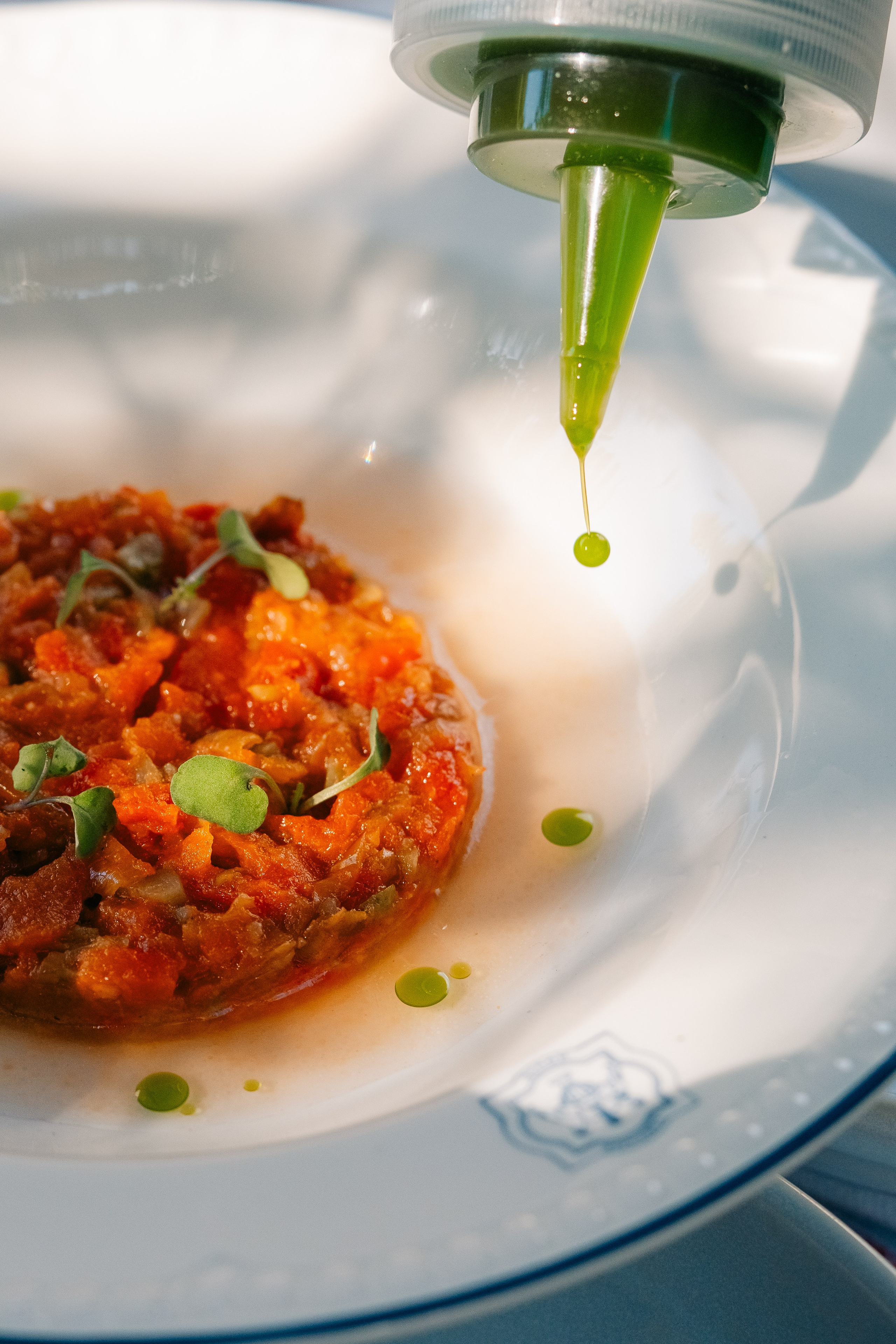 Grande plano de tártaro vegetal gourmet com guarnição de óleo verde. Grande plano de um tártaro vegetal a ser decorado com óleo verde de uma garrafa de precisão