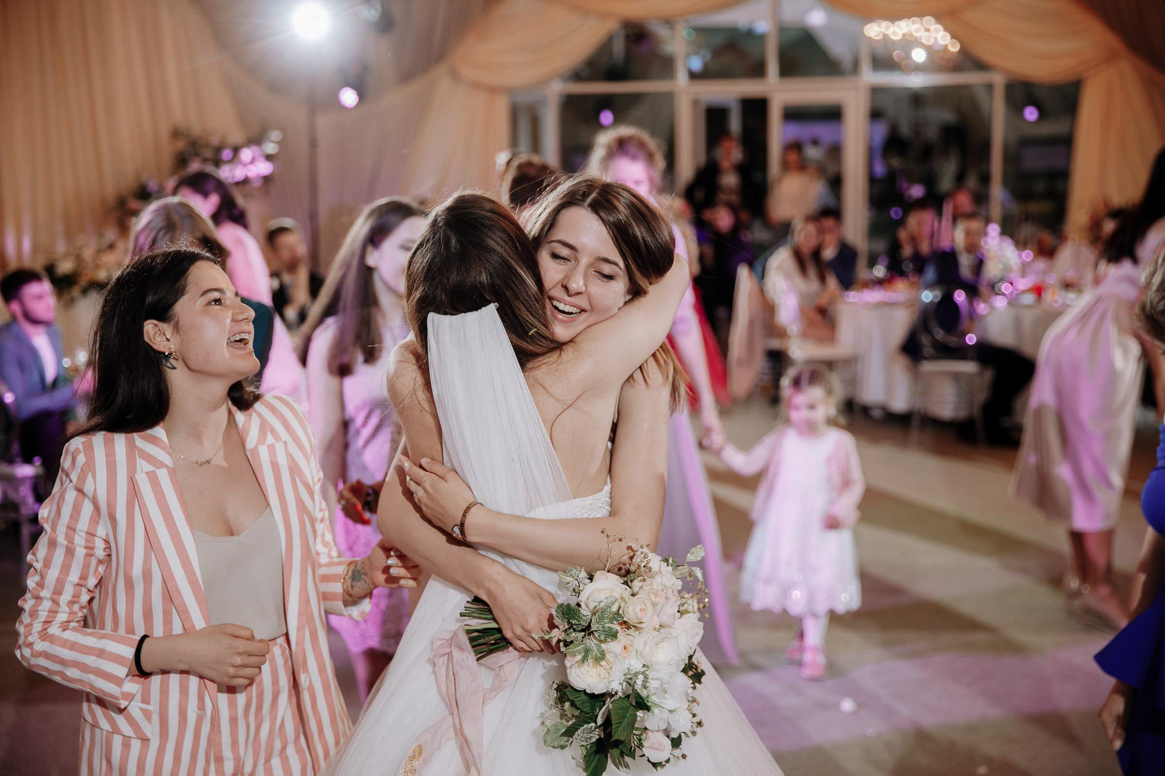 Bouquet toss winner hugs bride, by Tanya Bodgan, Devon wedding photographer.