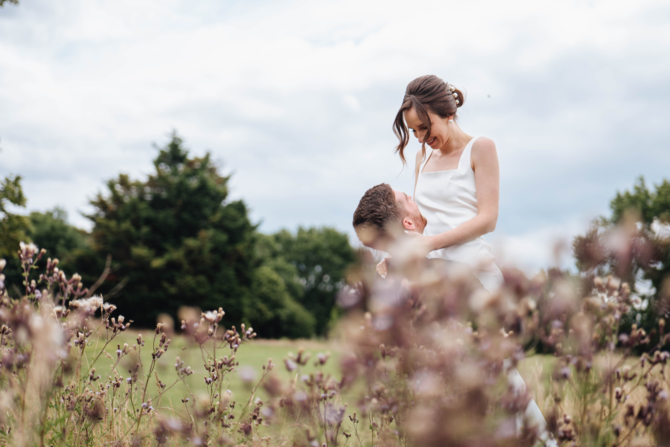 moody photo of bride and groom are looking at each other in fields