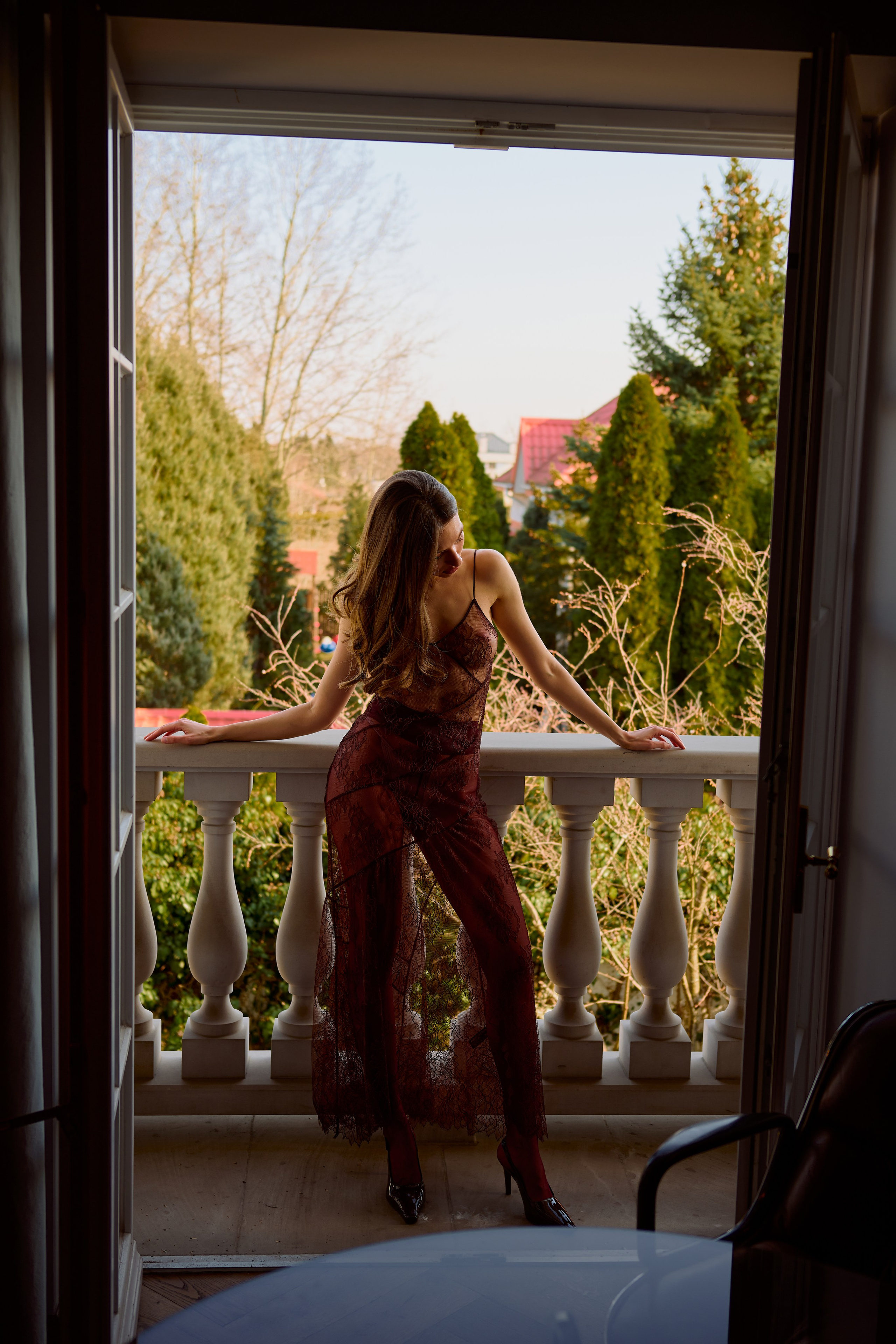 Fotografia kobieca z naturalnym światłem – kobieta w bordowej sukni na tarasie, artystyczna sesja zdjęciowa