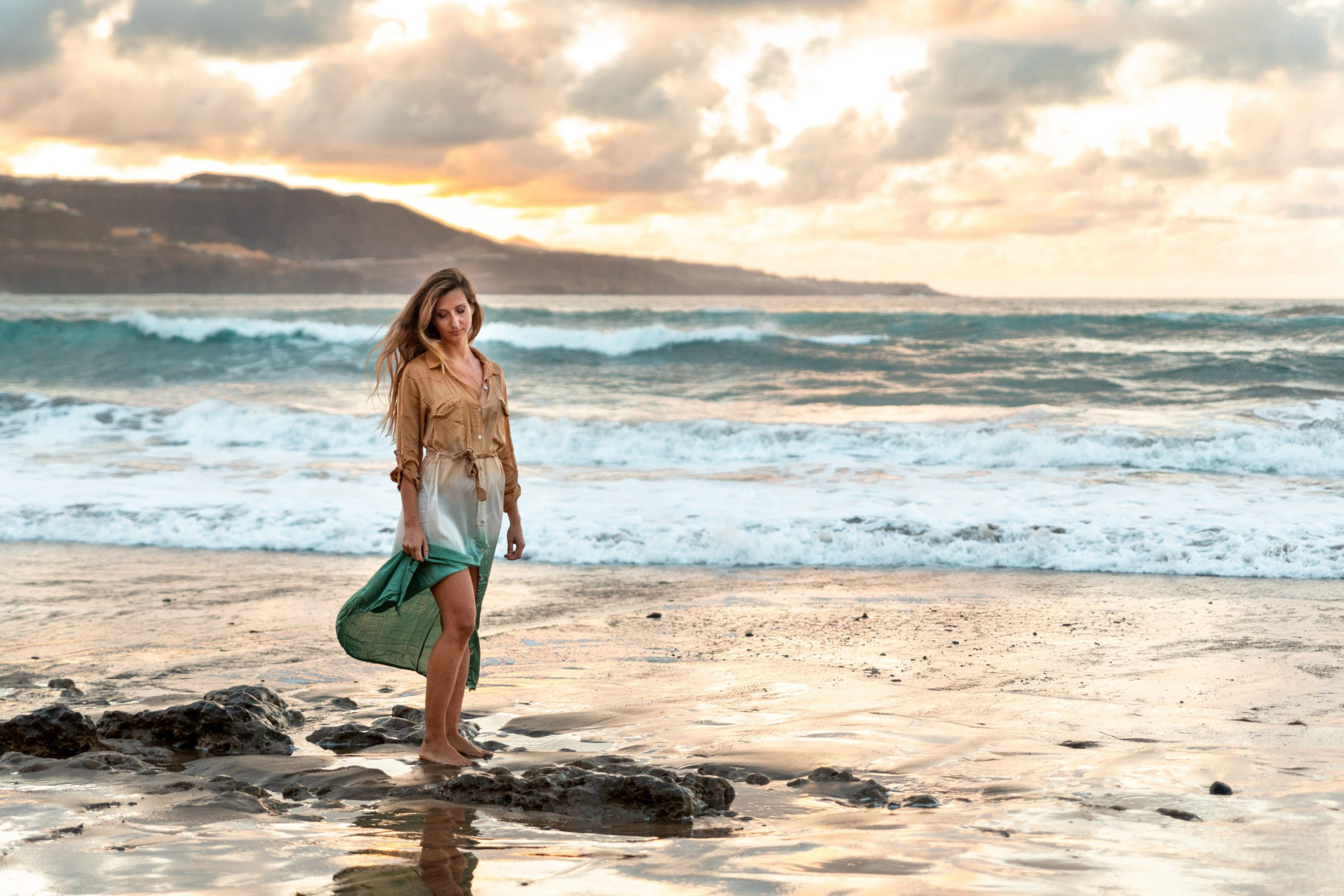 A woman standing on the beach at sunset Las Canteras Beach