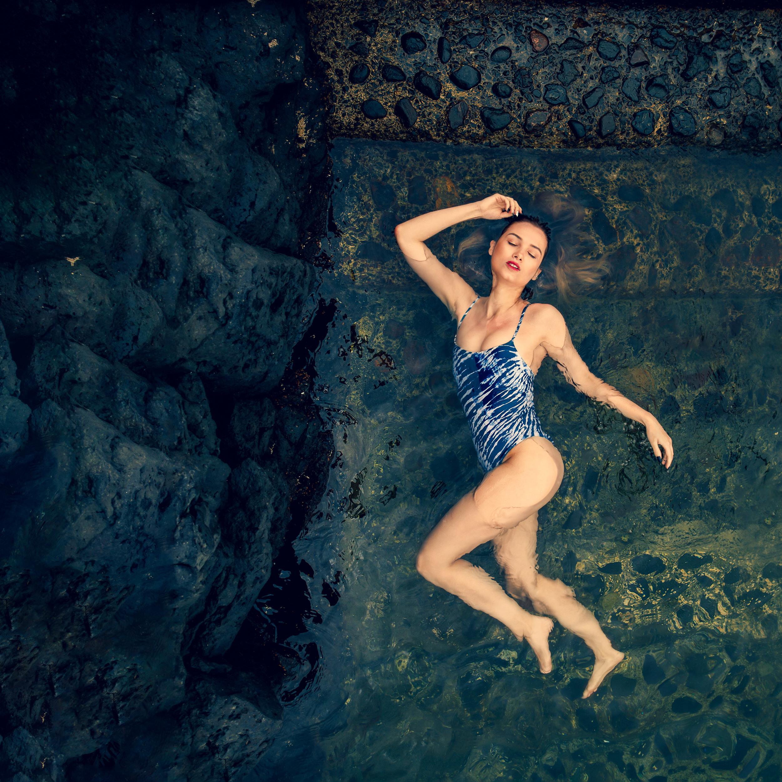 A woman in a blue swimsuit floating in the water.