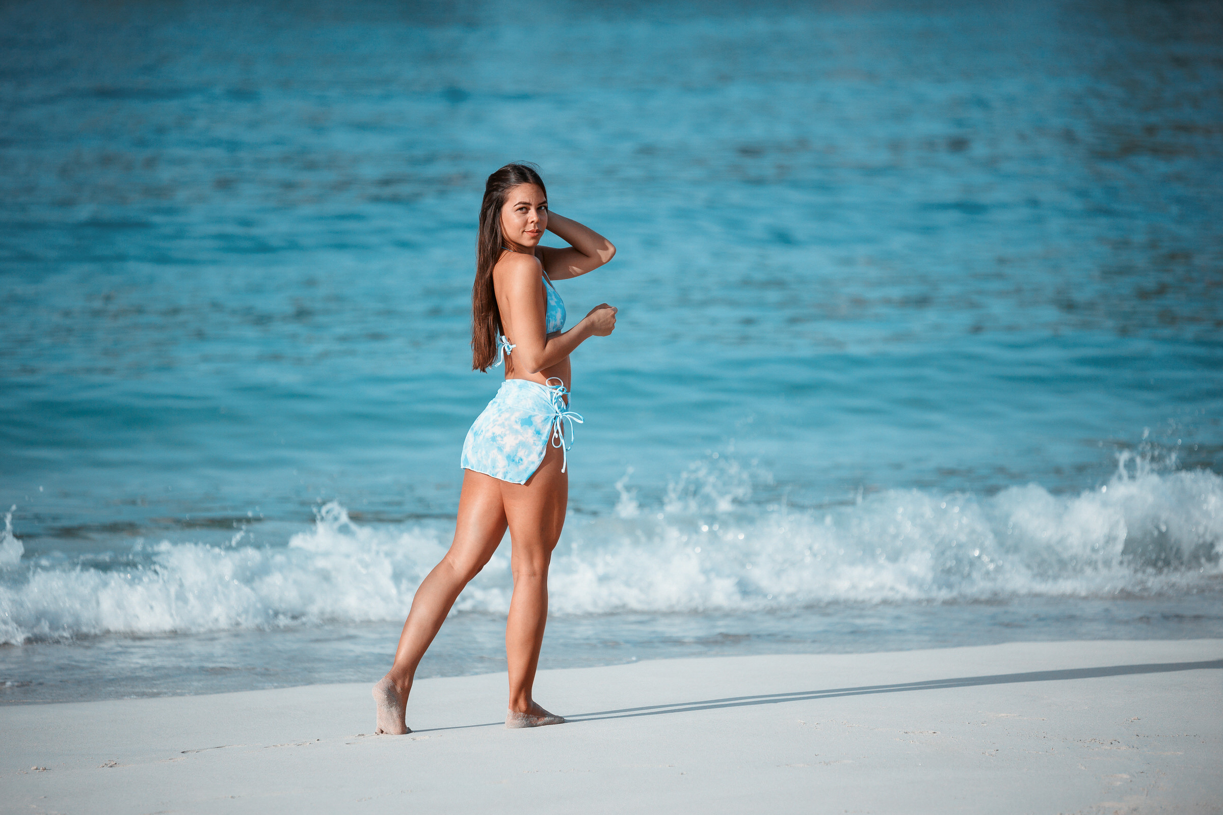 A woman in a blue bikini standing on the Anfi beach.