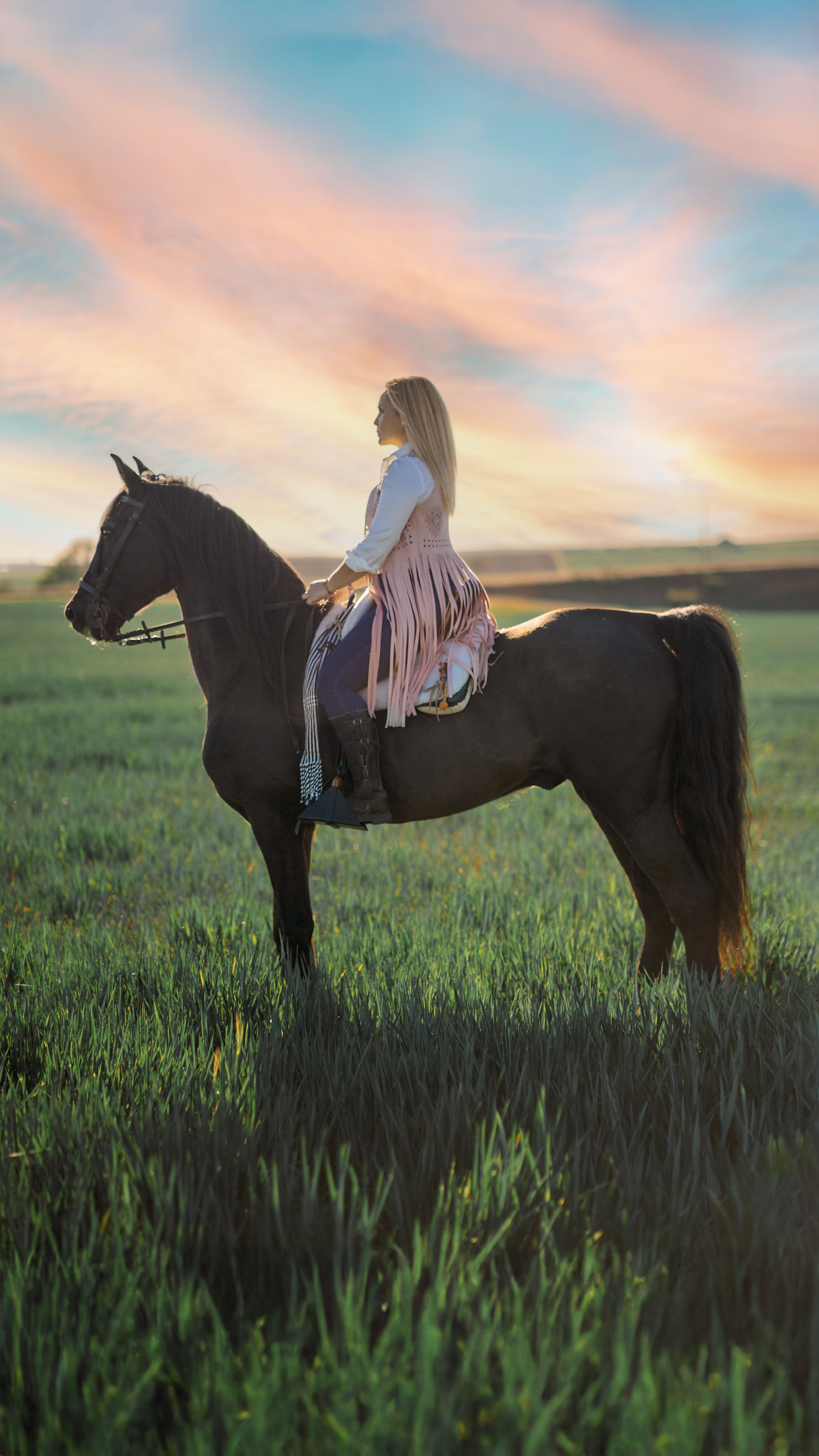 Joven elegante con un vestido junto a un caballo en el campo.