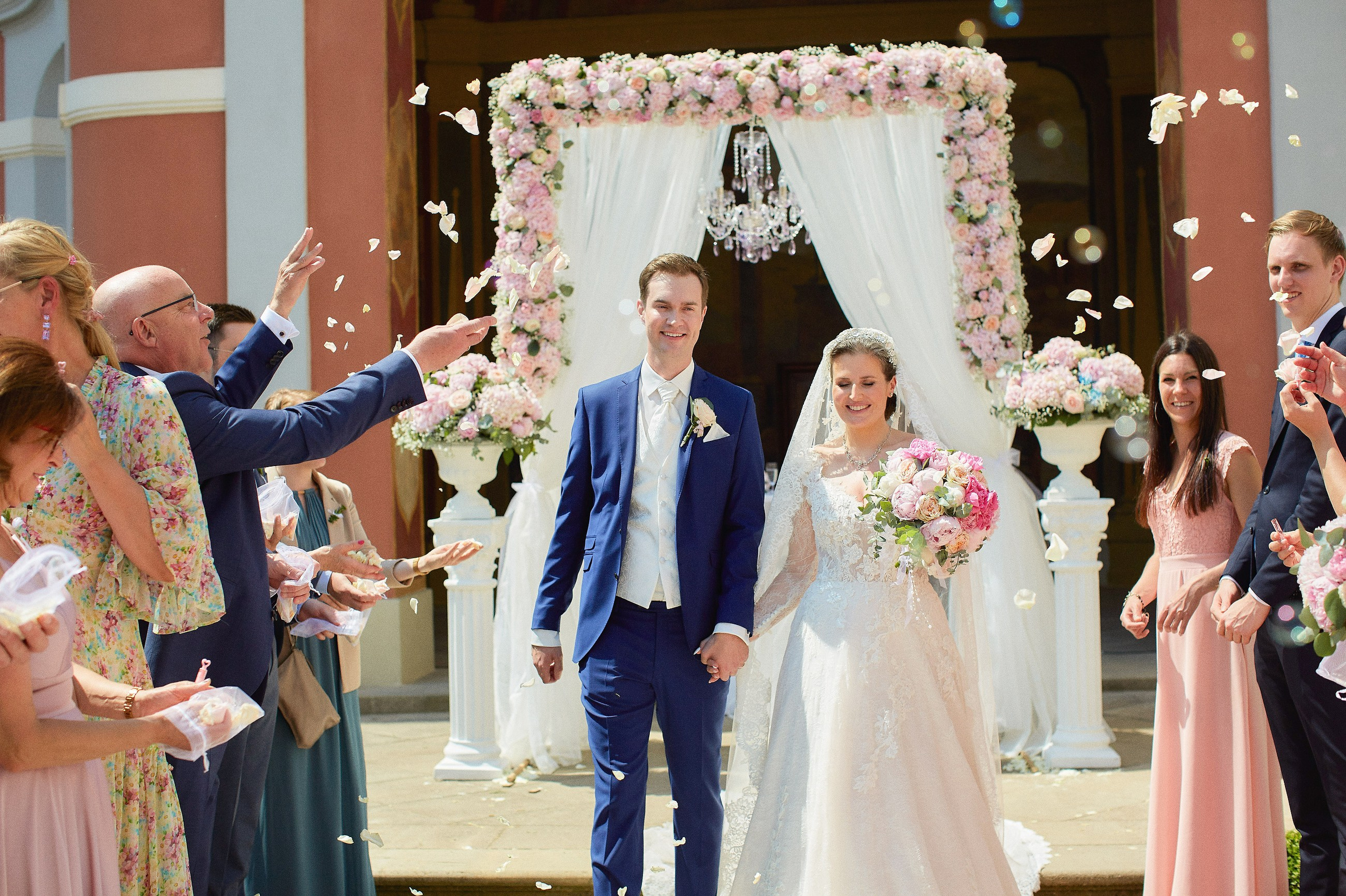 As bubles are blown and rose petals tossed, a smiling bride and groom make their way through their guests at the Ledebour Garden.