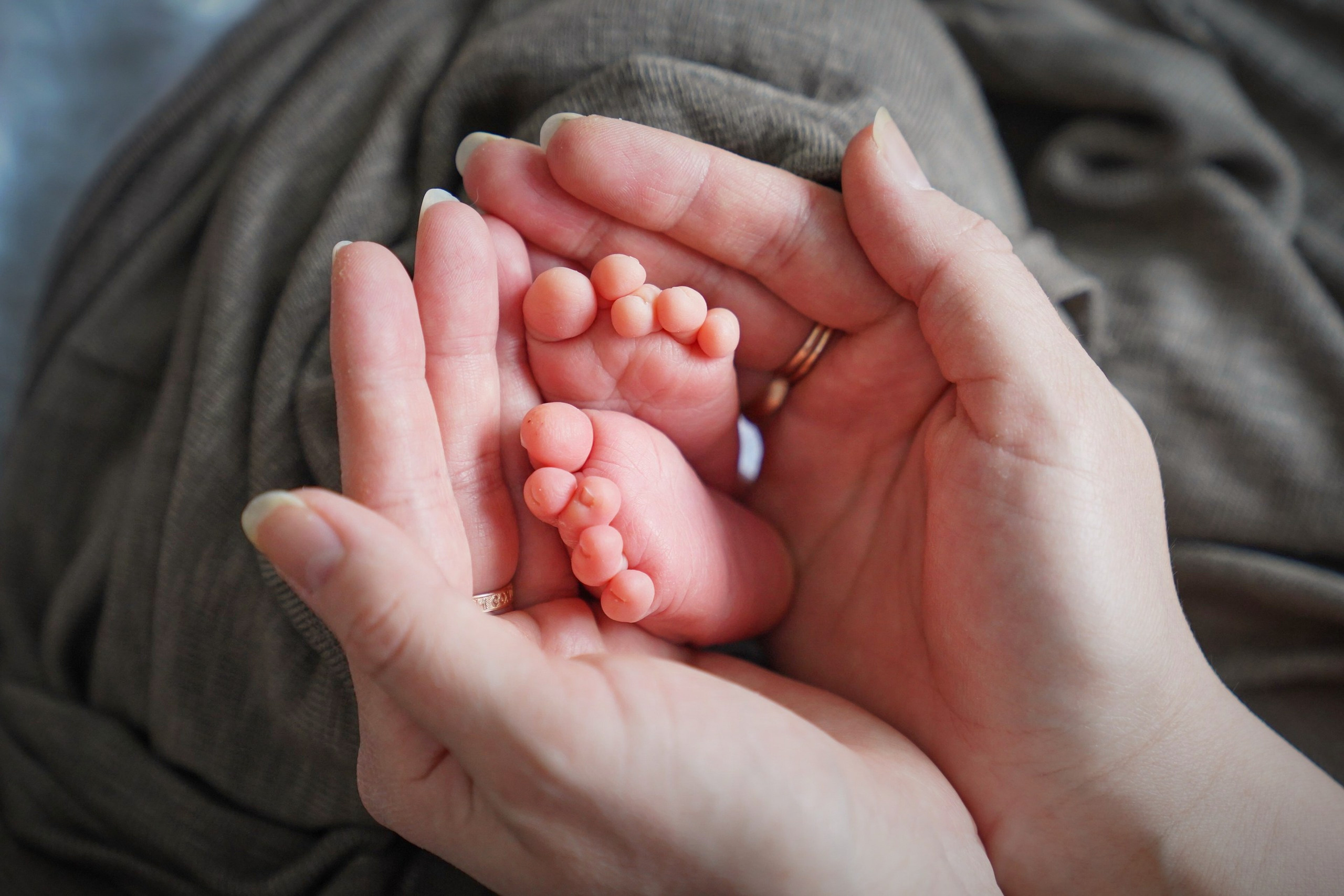 Mother cradling newborn baby's tiny feet in her hands