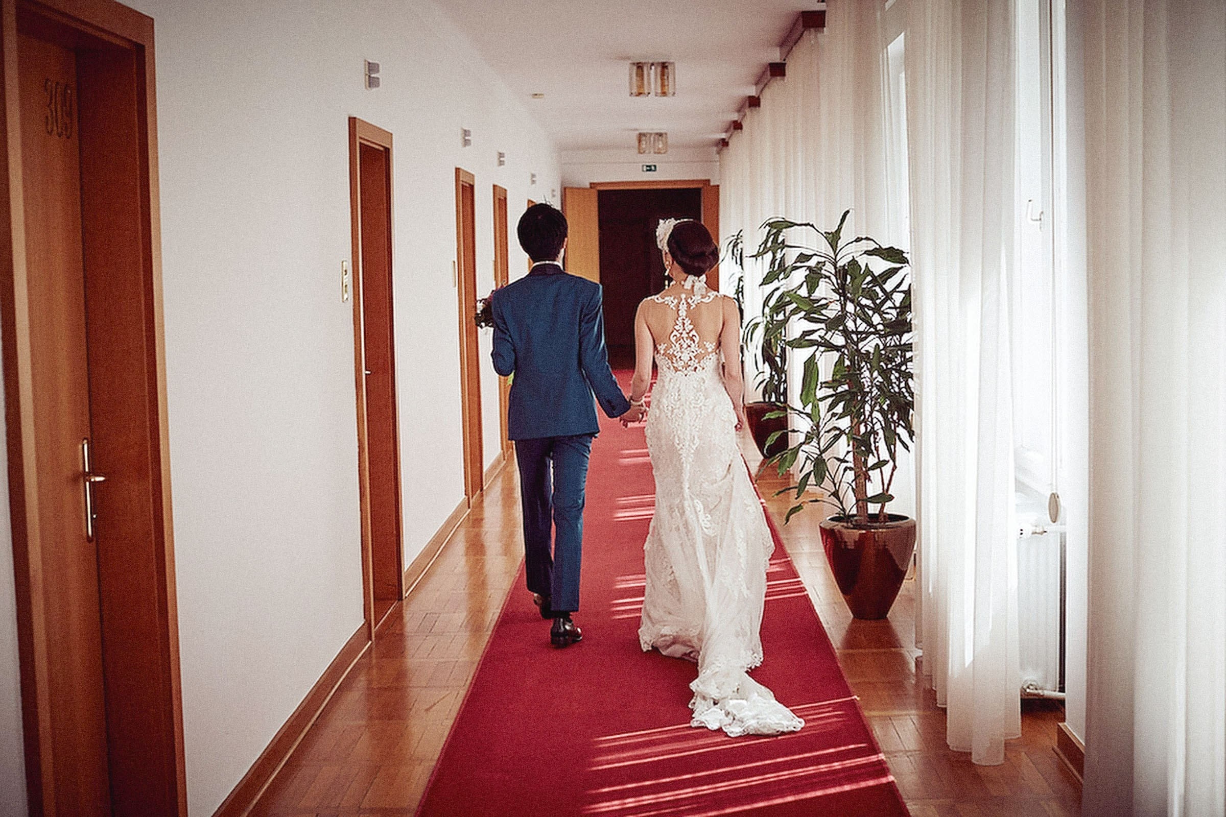 A bride and groom walk through the red-carpeted Vila Bled on the way to their wedding ceremony.