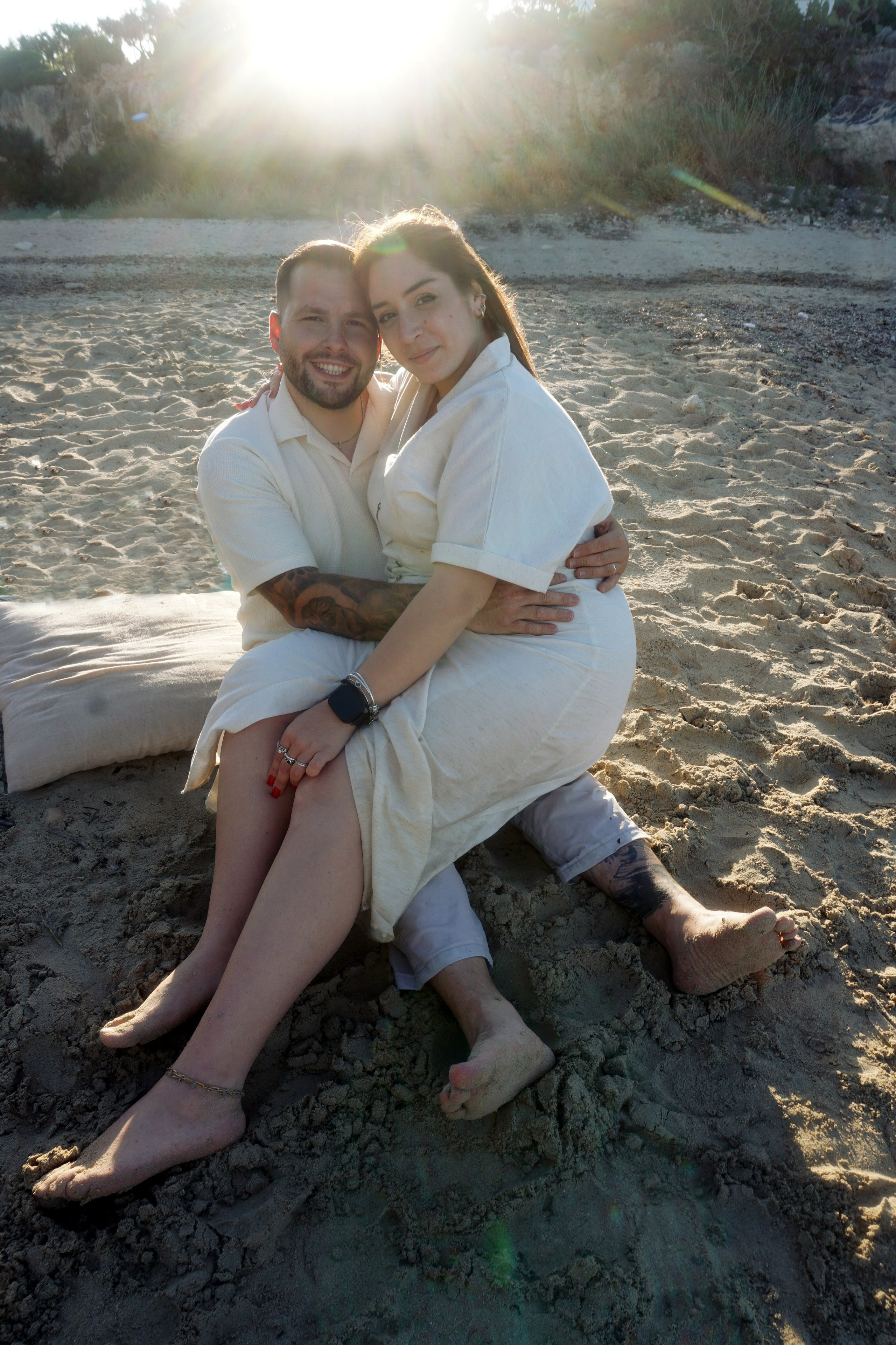 Mamma e papà che si abbracciano mentre i bambini giocano tra le onde di Polignano a Mare.