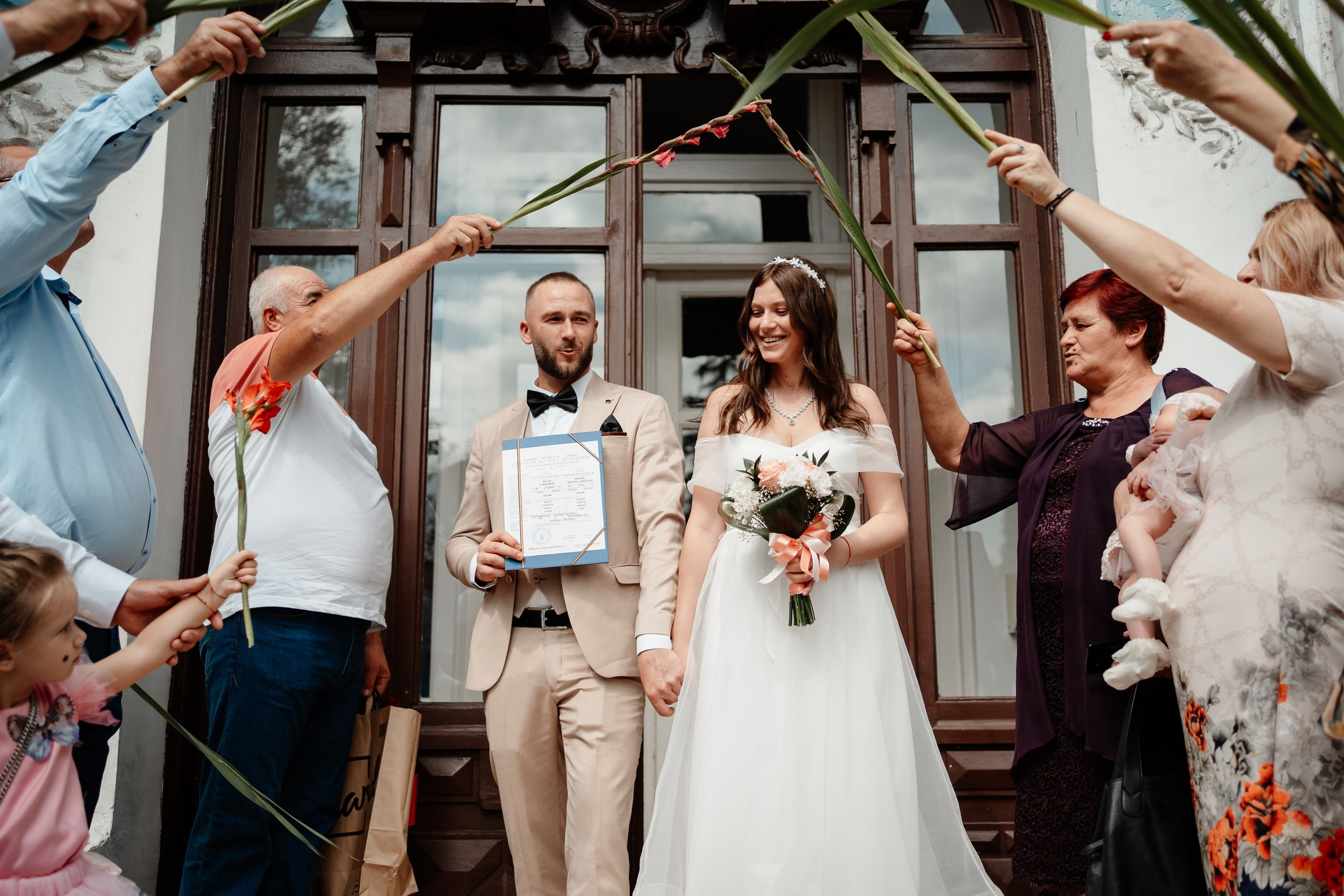 Miri fericiți în fața oficiului stării civile din Bucuresti, Sector 1, celebrând începutul unei noi vieți împreună. Fotografie de cununie civilă, capturând naturalețea și bucuria momentului special.