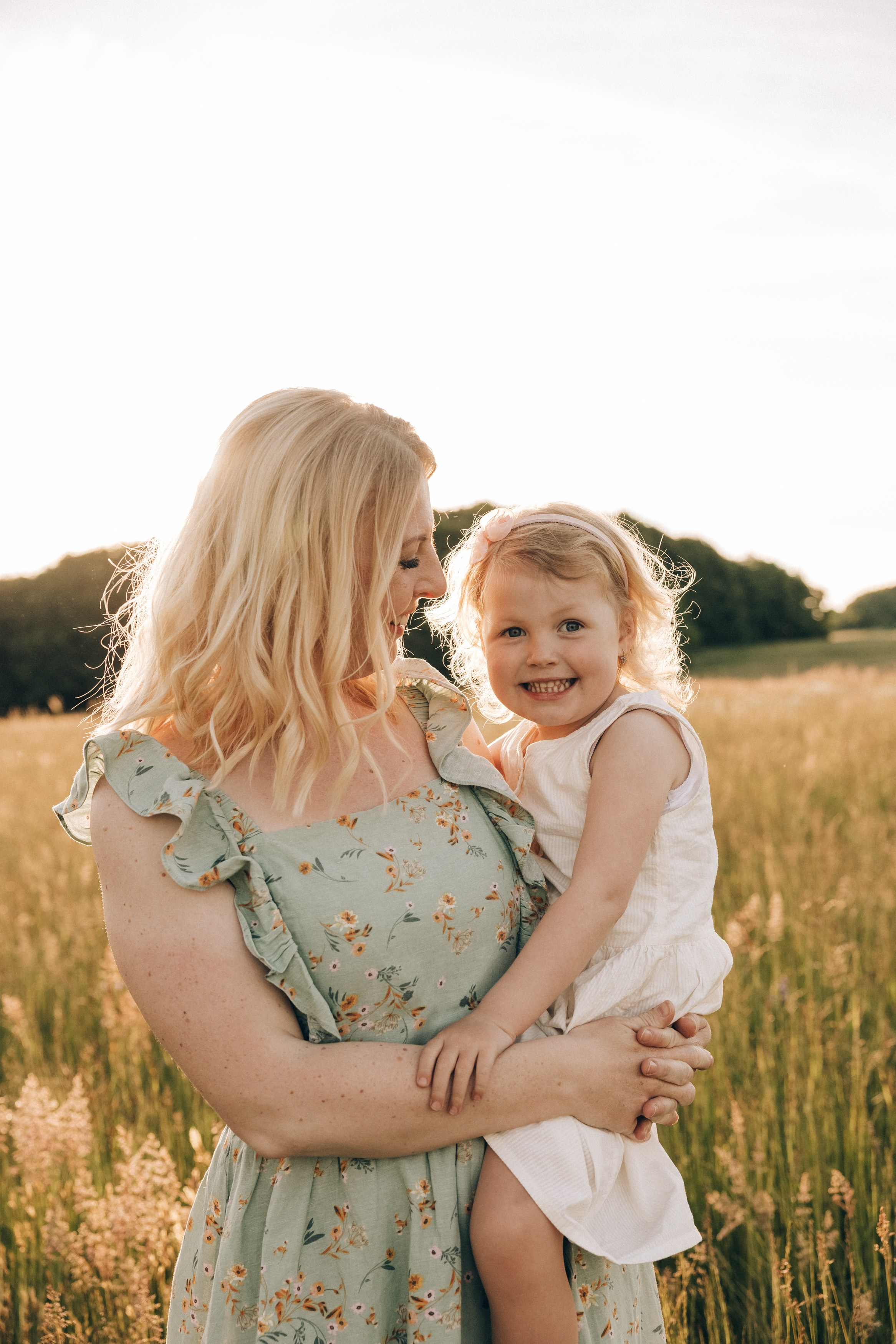 Family photoshoot in a daisy meadow at golden hour — natural light, warm tones, candid moments between a mother and her daughters. Lifestyle and Family Photographer in Pisek Oxana Telupilova