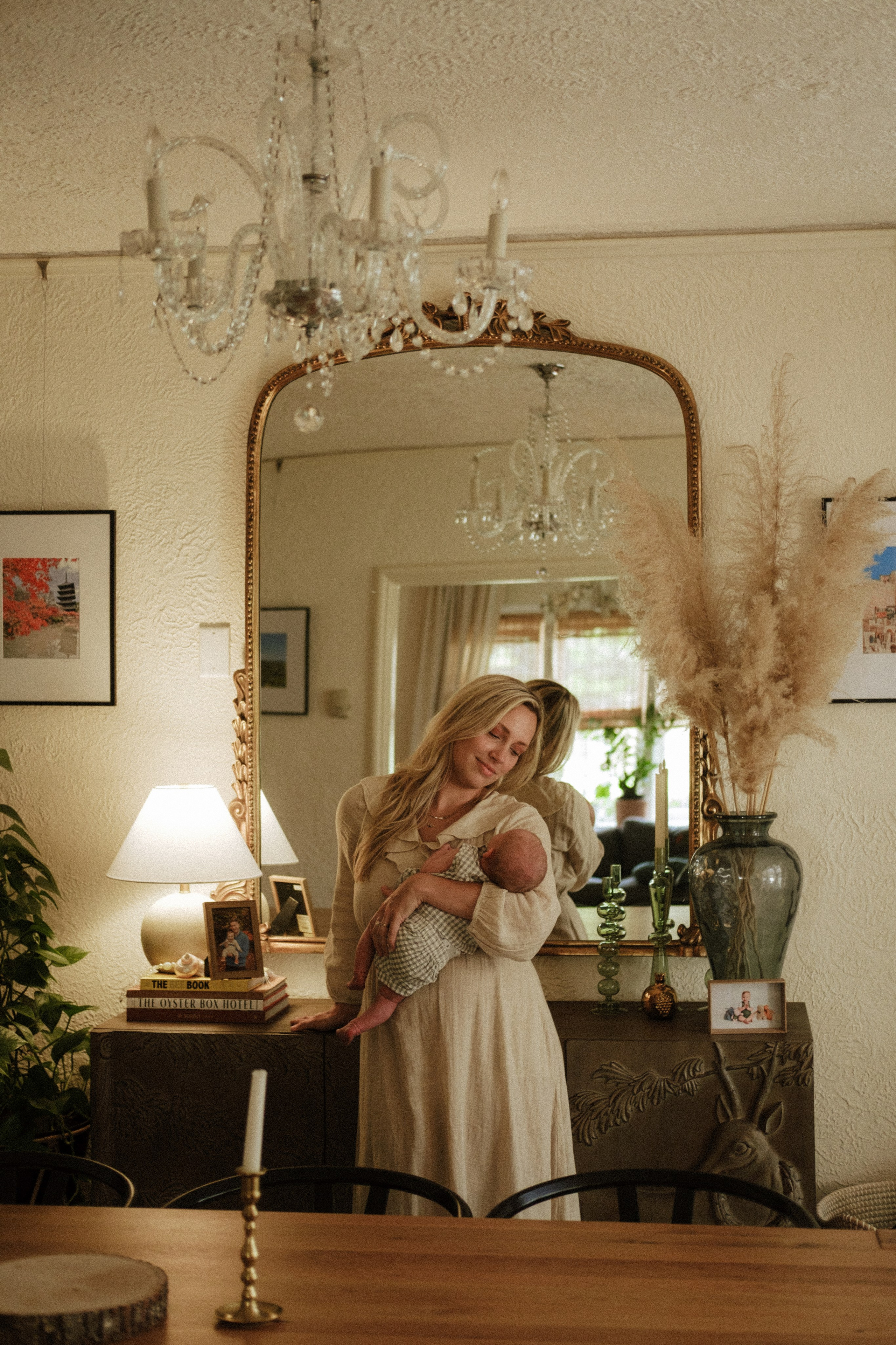 A mother standing by the mirror, holding her newbonr baby in her beautiful dining room in Richmond, VA