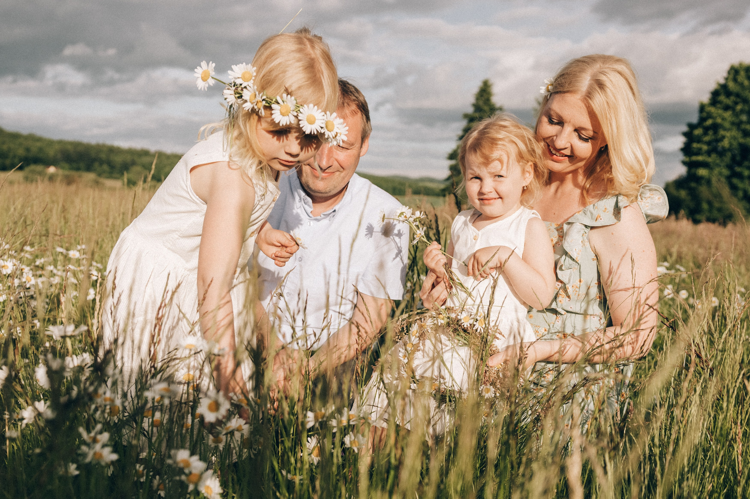 Family photoshoot in a daisy meadow at golden hour — natural light, warm tones, candid moments between a mother and her daughters. Lifestyle and Family Photographer in Pisek Oxana Telupilova