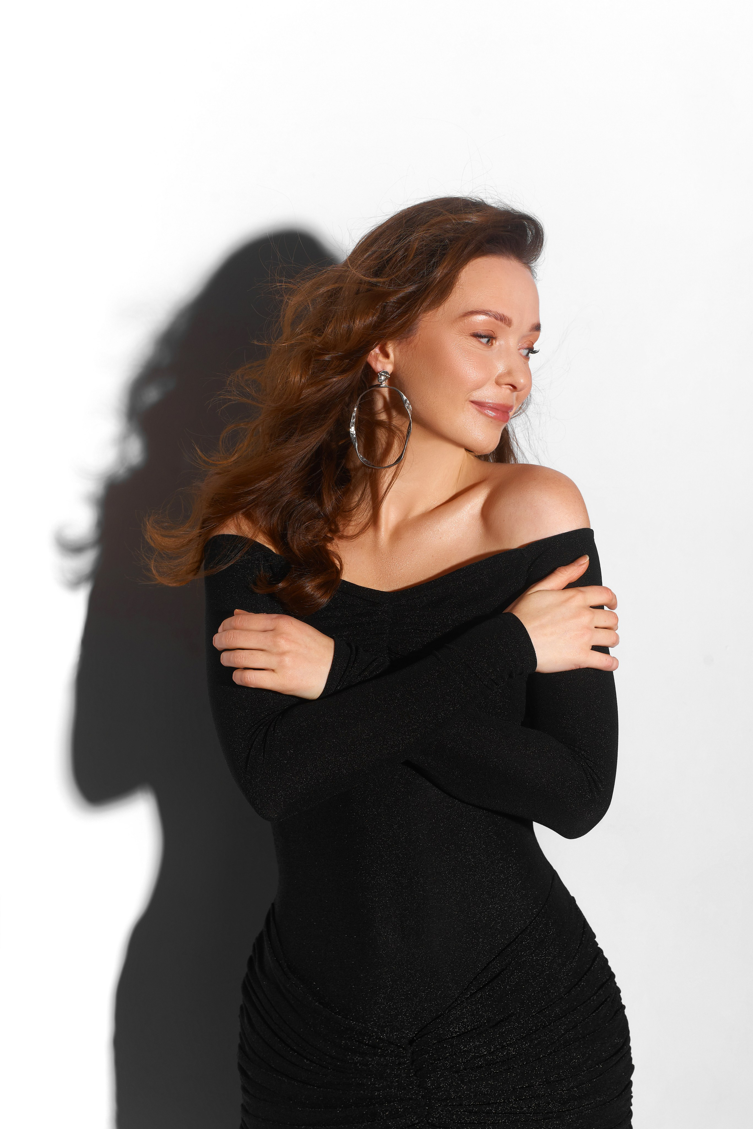 Portret studyjny z grą światła – kobieta w eleganckiej czarnej sukience, subtelna kobiecość i zmysłowość