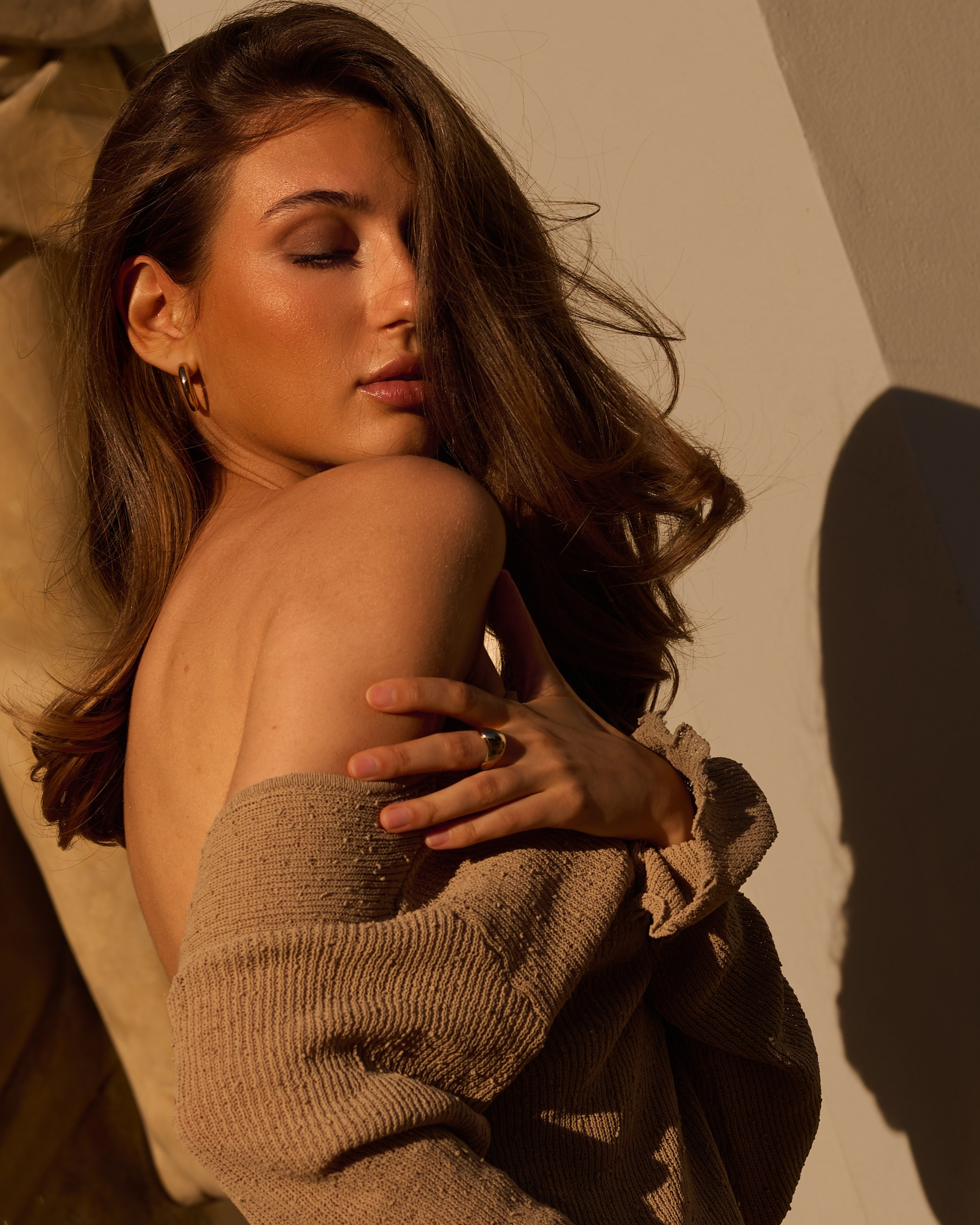 Бежевий образ у вечірньому сонячному світлі, жінка спирається на колону біля палацу.