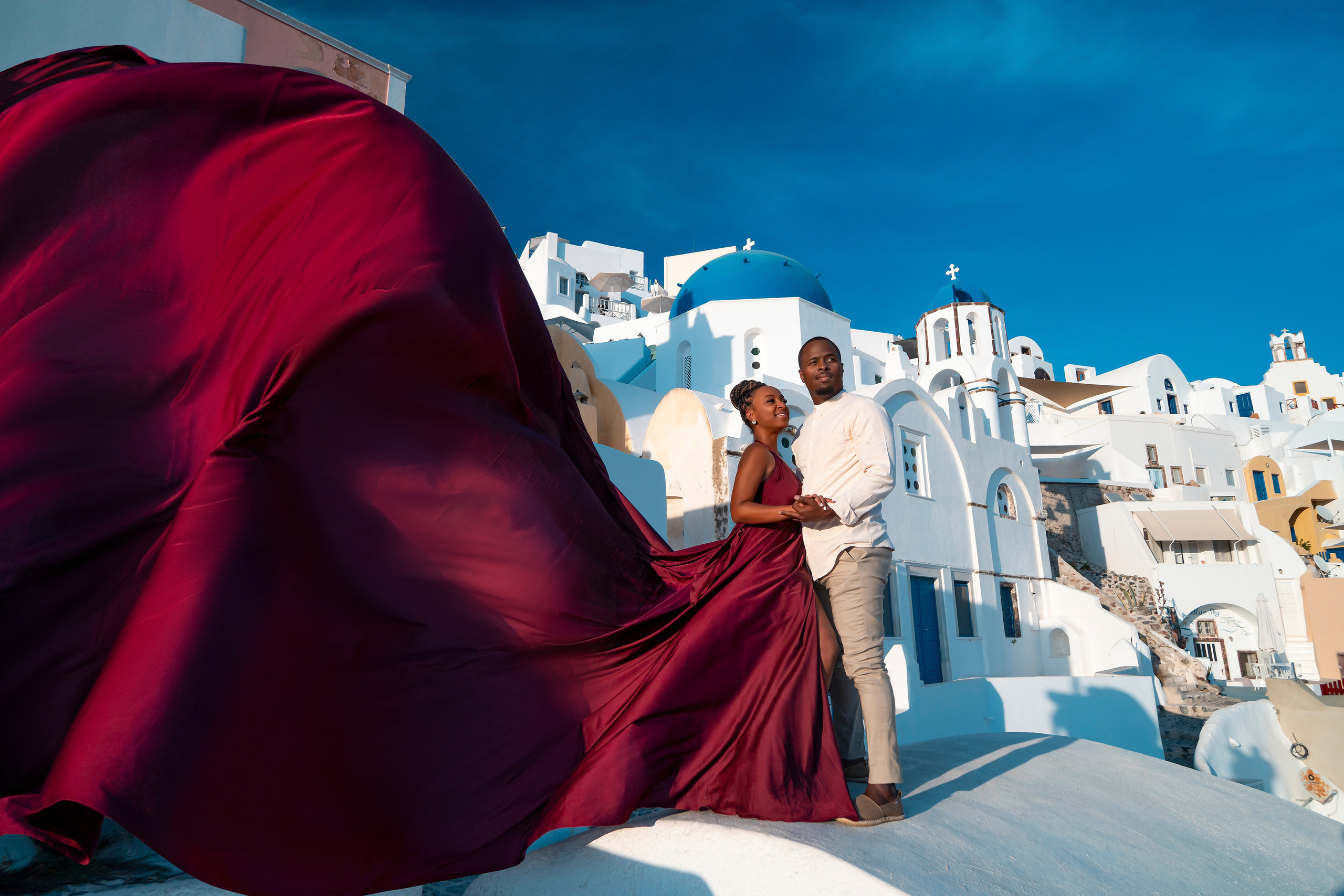 Photo session in Oia, Santorini at sunset, cherry flying dress. Photographer in Santorini SokoLOVE Alex| Flying Dress Santorini