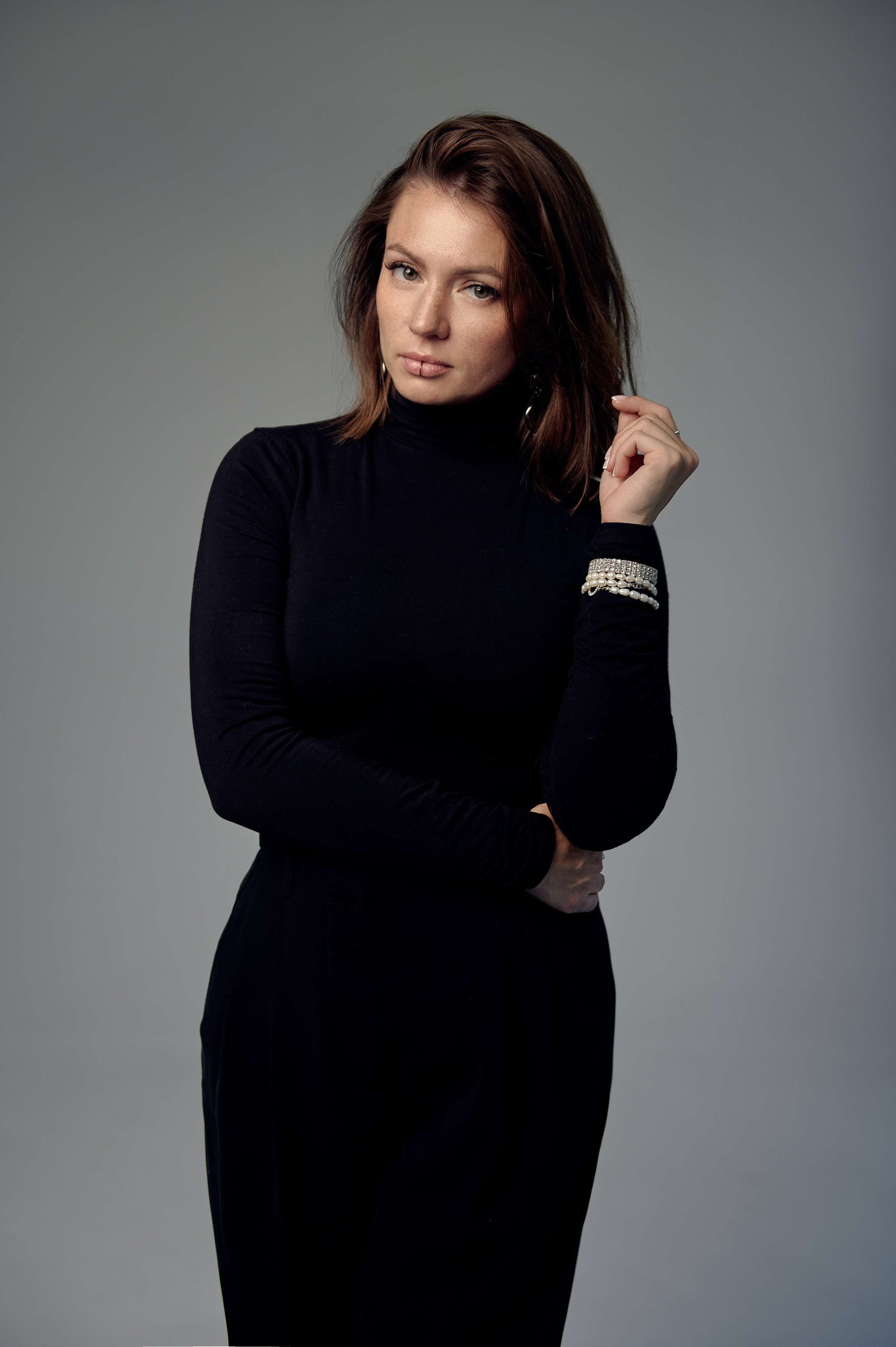 Kobieta w czarnym golfie z biżuterią