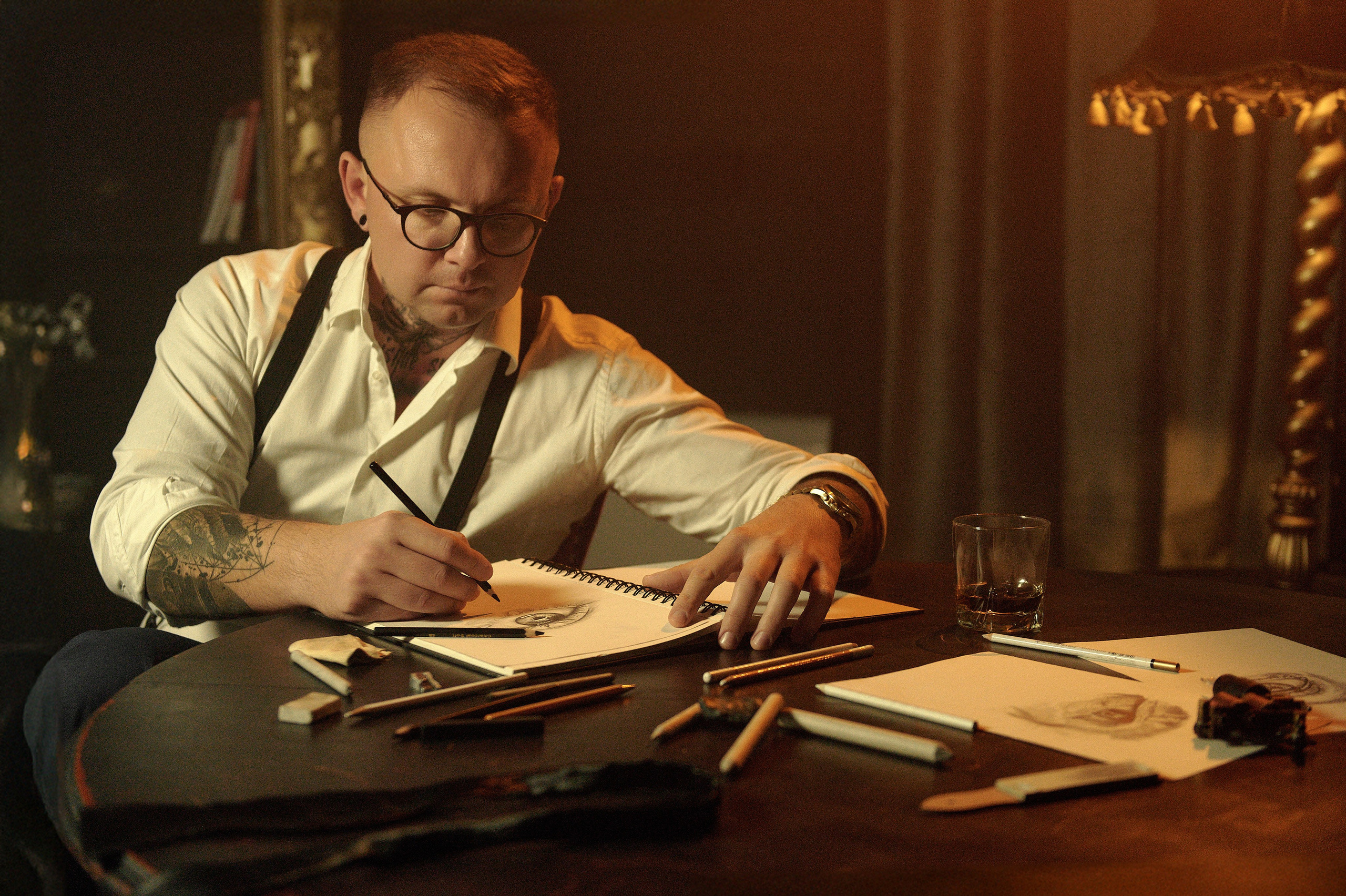 Mężczyzna rysuje ołówkiem w szkicowniku – skupienie, detale artystycznej pracy