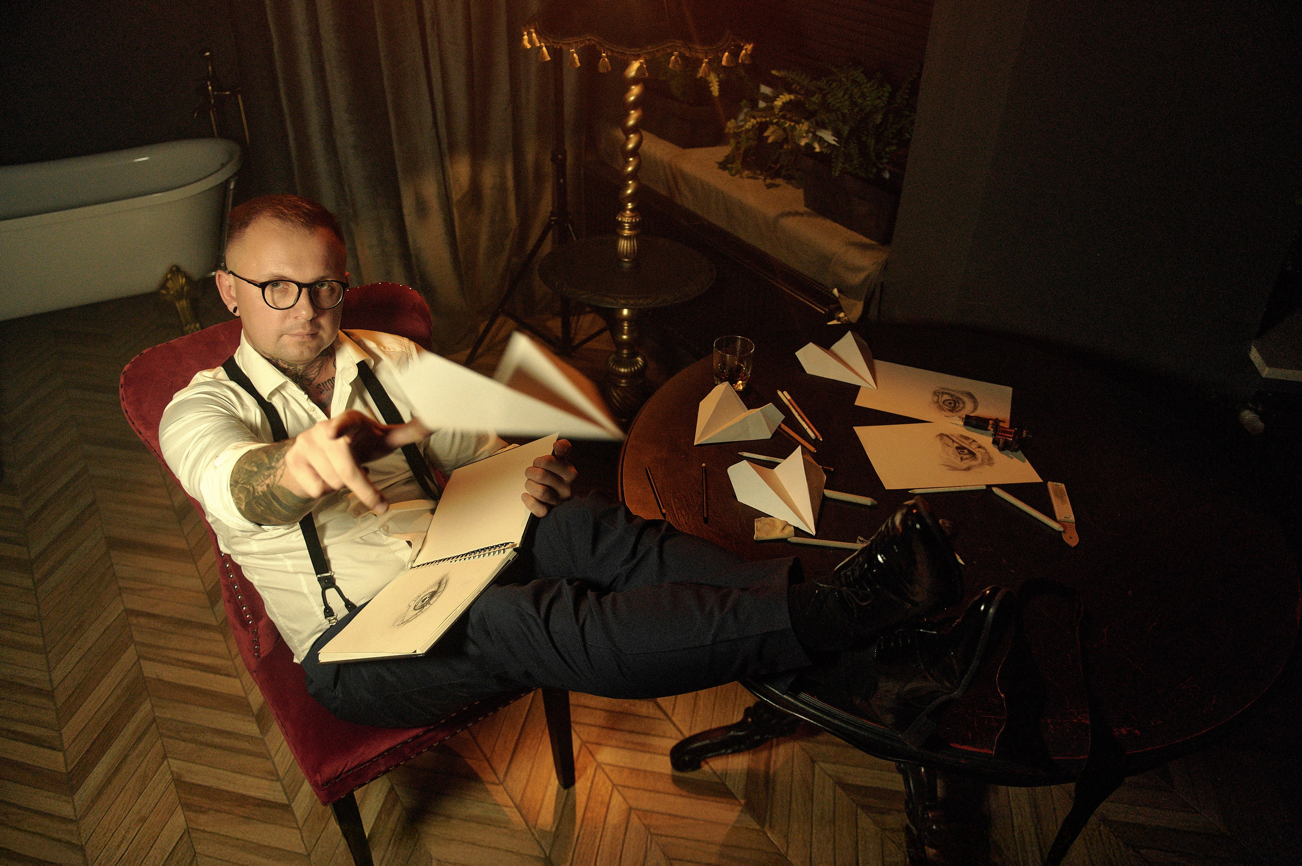 Portret, mężczyzna rzuca papierowy samolot, wokół szkice i ołów