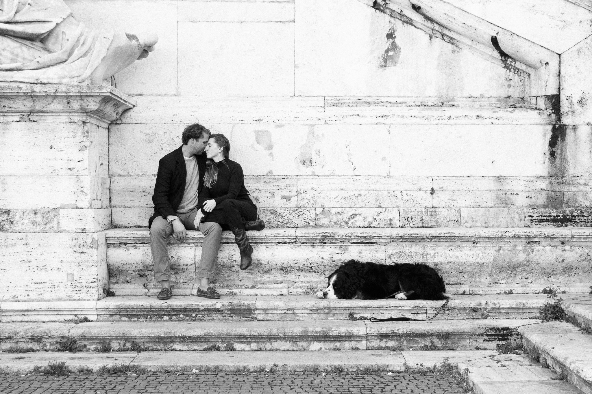 A couple hugging in Rome's historic streets dog sleeping.