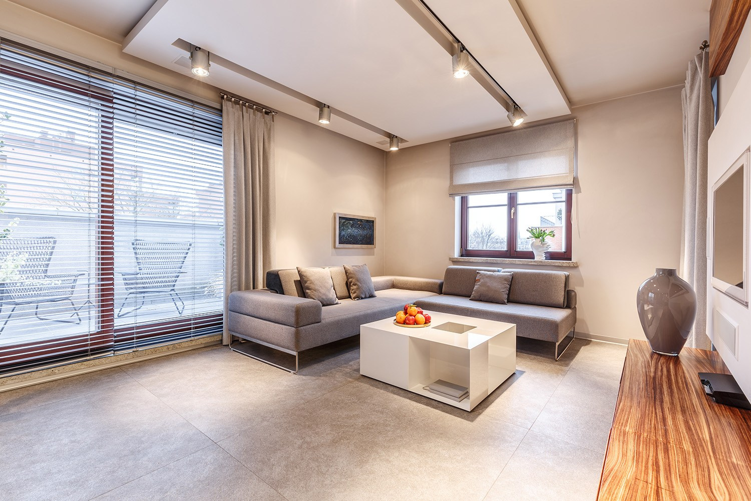Stylish renovated living room featuring a modern plasterboard ceiling, new flooring, and large balcony doors, illustrating an Athens apartment transformation.