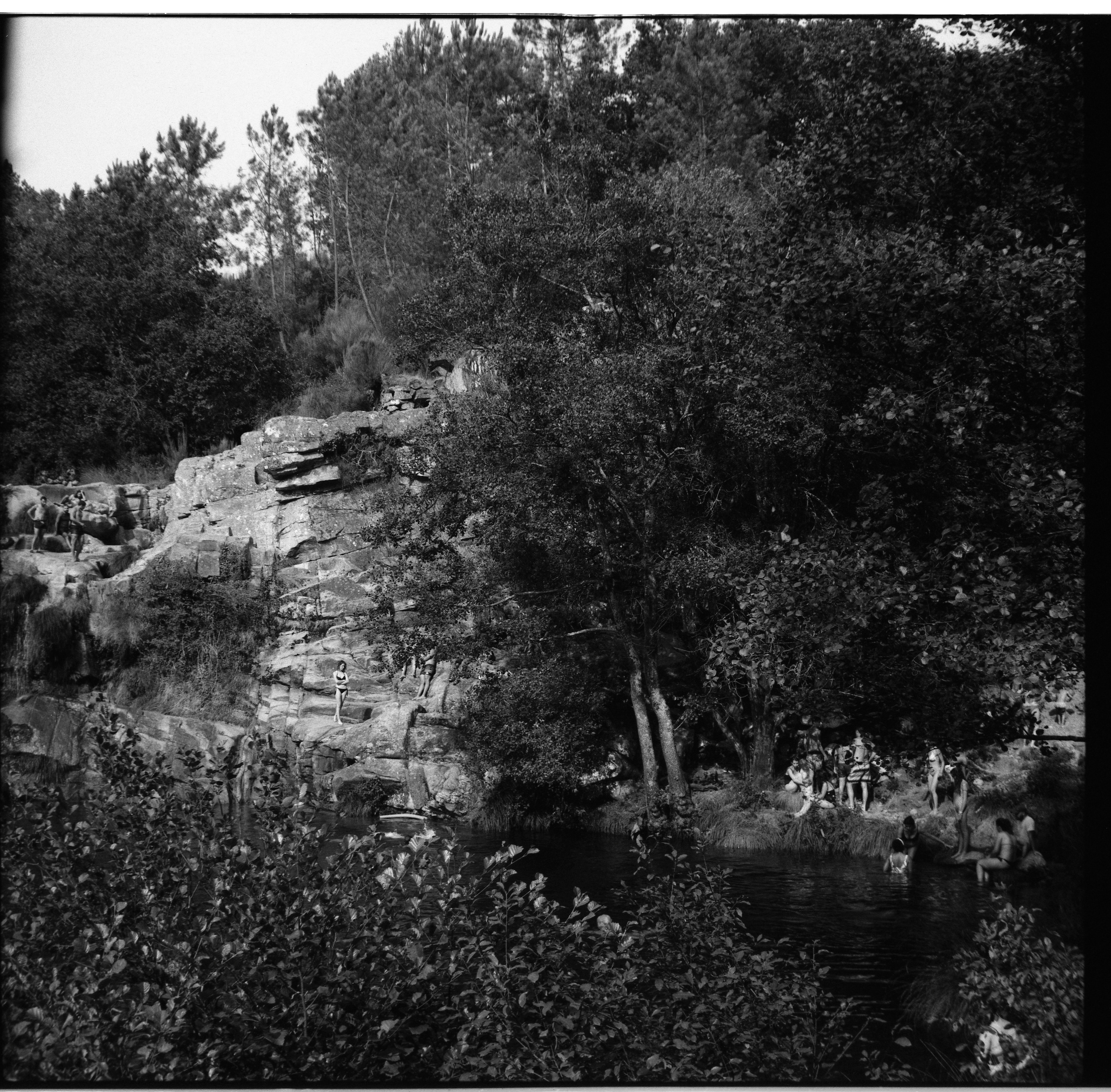 Documentaire fine art fotografie, zomer in Portugal. Locals, oude mensen, jongens, meisjes, mannen en vrouwen met baby's genieten van de koelte van een waterval in het bos.