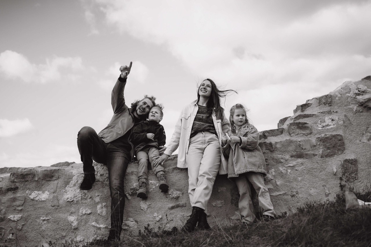 Fröhliche Familie mit zwei Kindern bei einem Outdoor-Fotoshooting – Moment voller Lebensfreude auf einer Steinmauer nahe Nürnberg