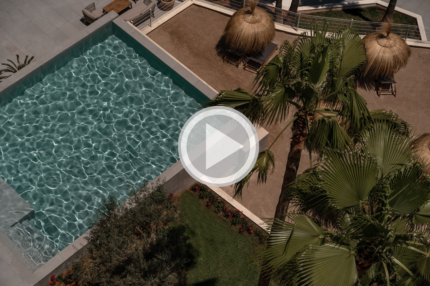 People relaxing in the shade of palm trees at a swimming pool, photographed by George Katsaelis
