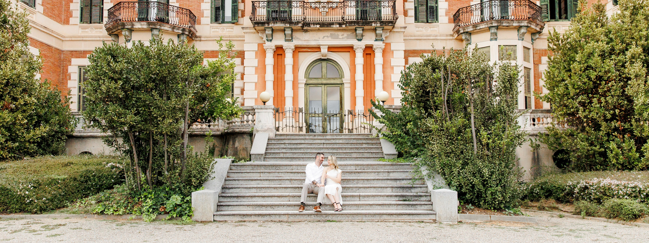 Couple sitting on a staircase of a historical park during their engagement session in Barcelona