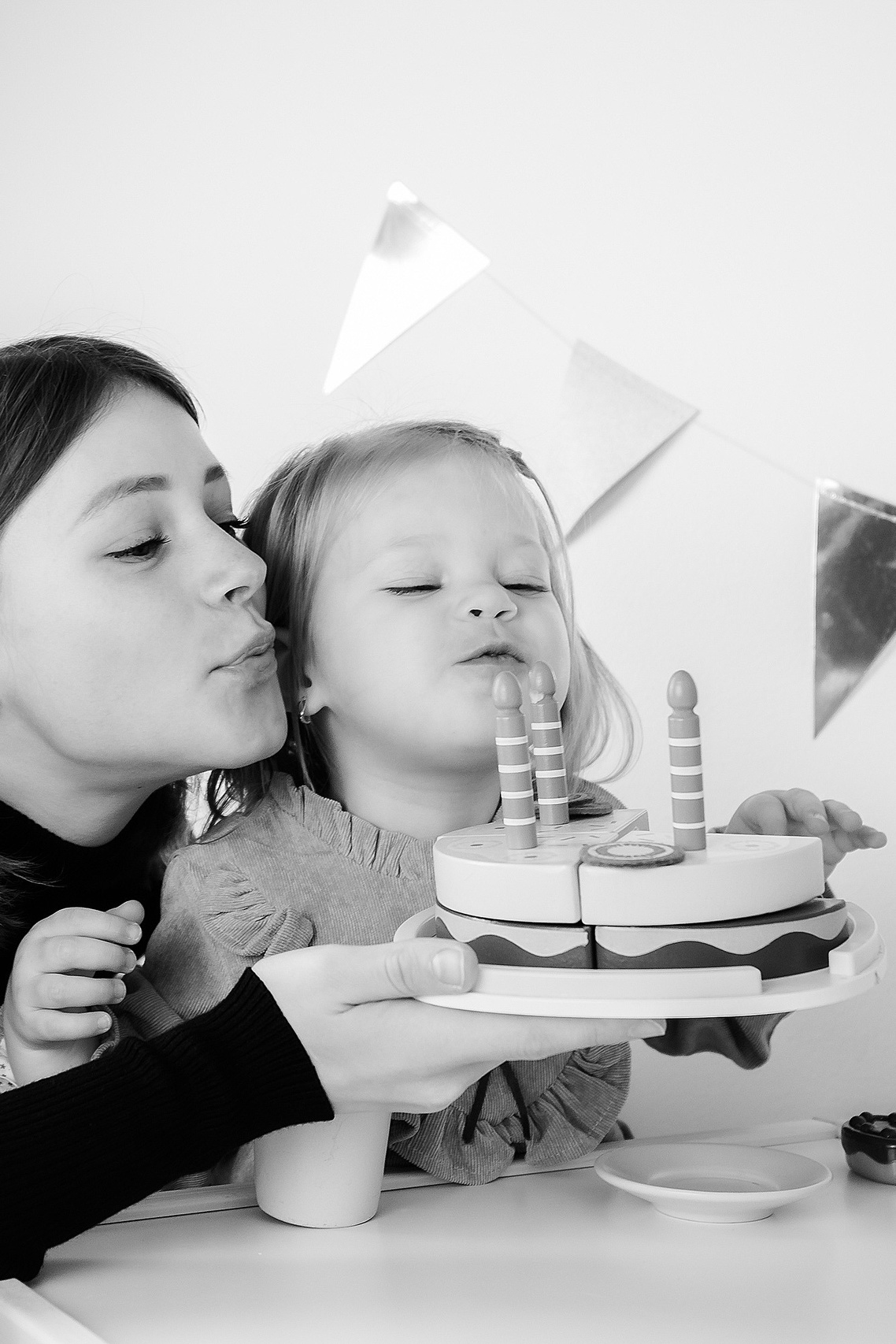 Счастливая мама помогает своему малышу задуть свечу на торте в честь его дня рождения. Вокруг витает атмосфера тепла и радости, а каждая маминская улыбка и нежное прикосновение создают незабываемые моменты счастья и любви, которые запечатлены в этой домашней фотостудии в Хельсинки