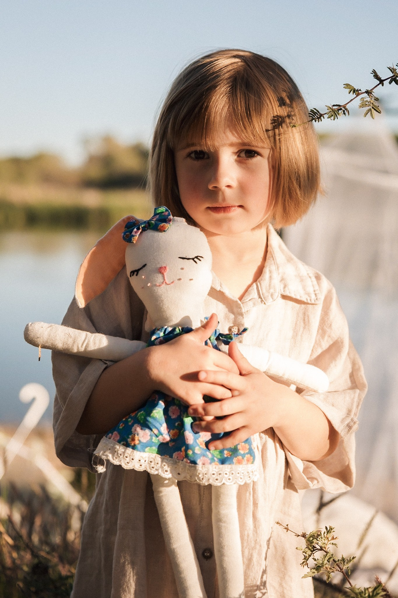 Preschool girl photoshoot with a cute rabbit by the lake in summer