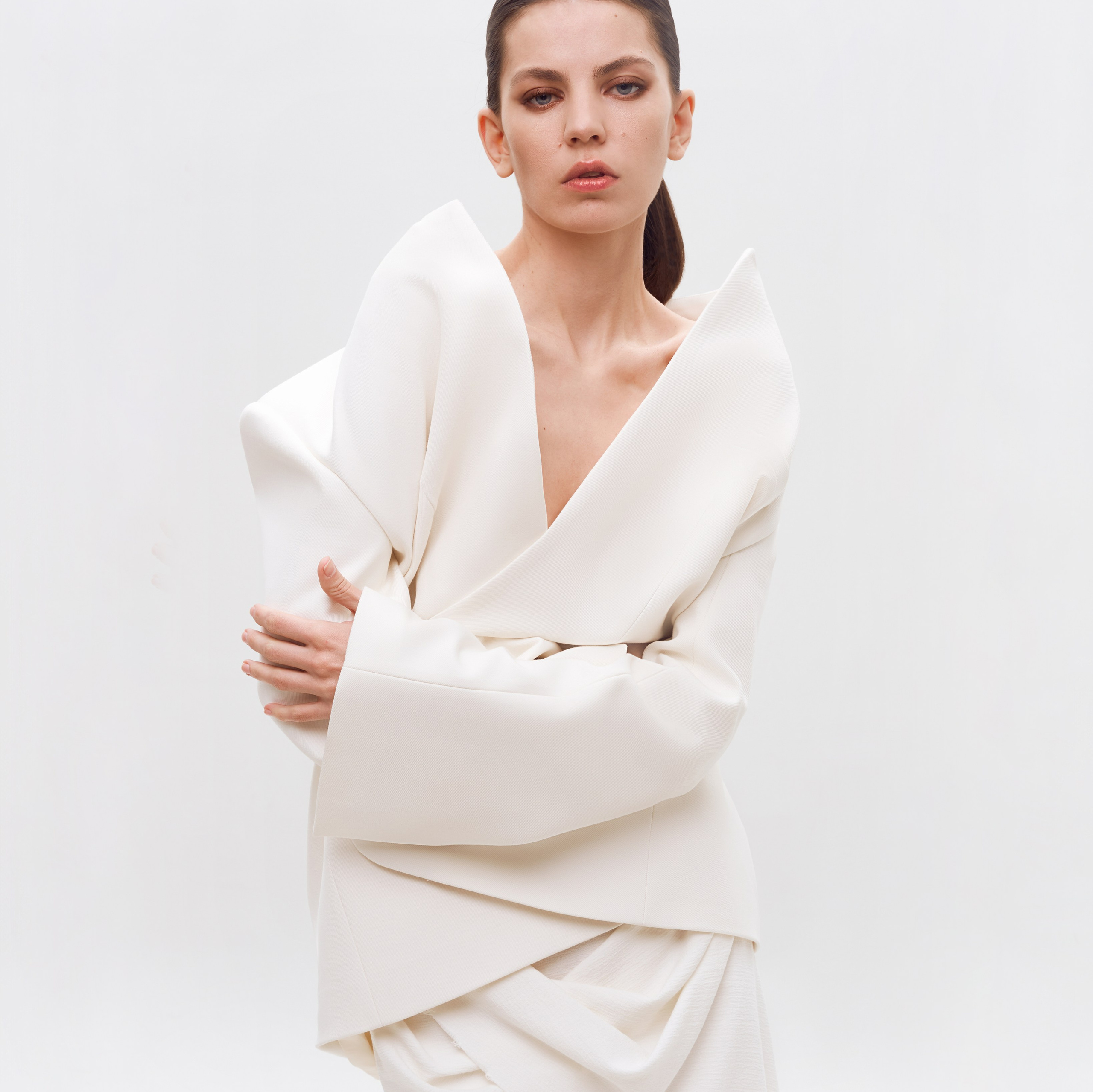 Fashion photographer Hanna Asaulova | Model in a stylish white suit with voluminous sleeves on a minimalist white background, professional portrait photoshoot in Vilnius.