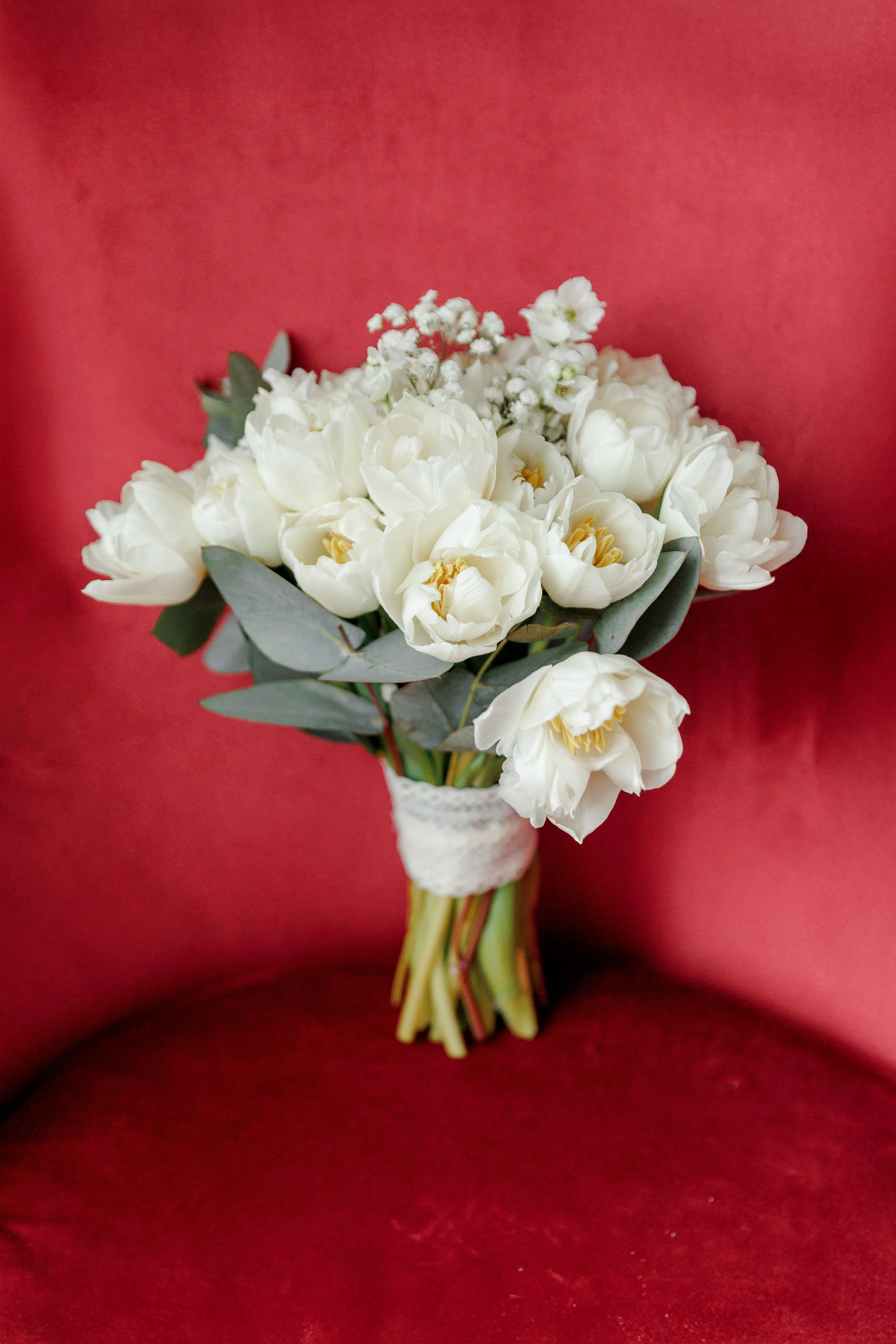 Bridal stylish bouquet staying on the red chair. 