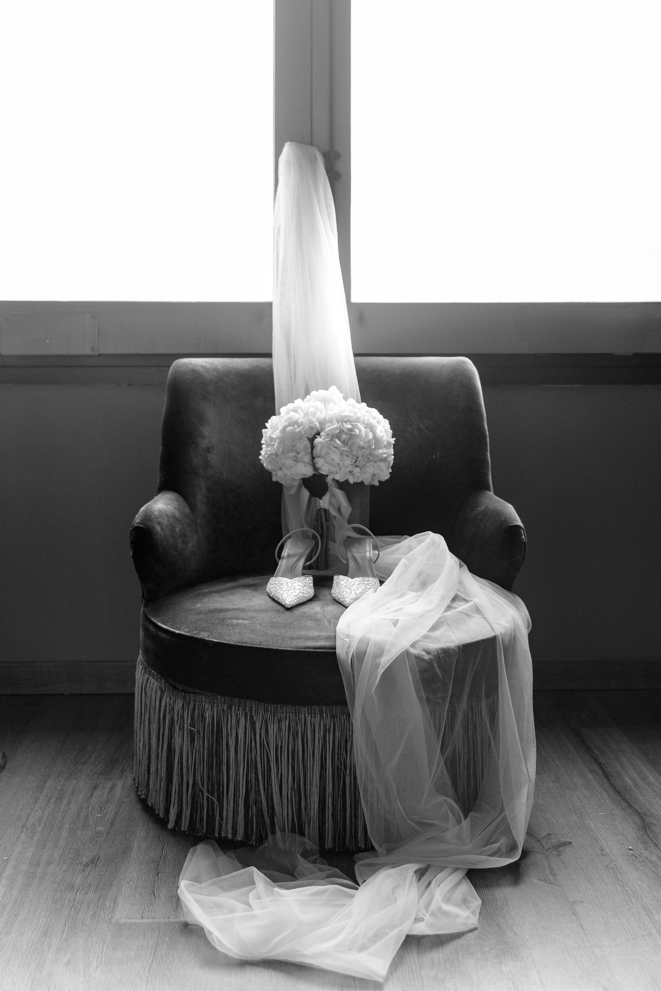 Close up shoot of a bridal veil, shoes and flowers in monochrome 