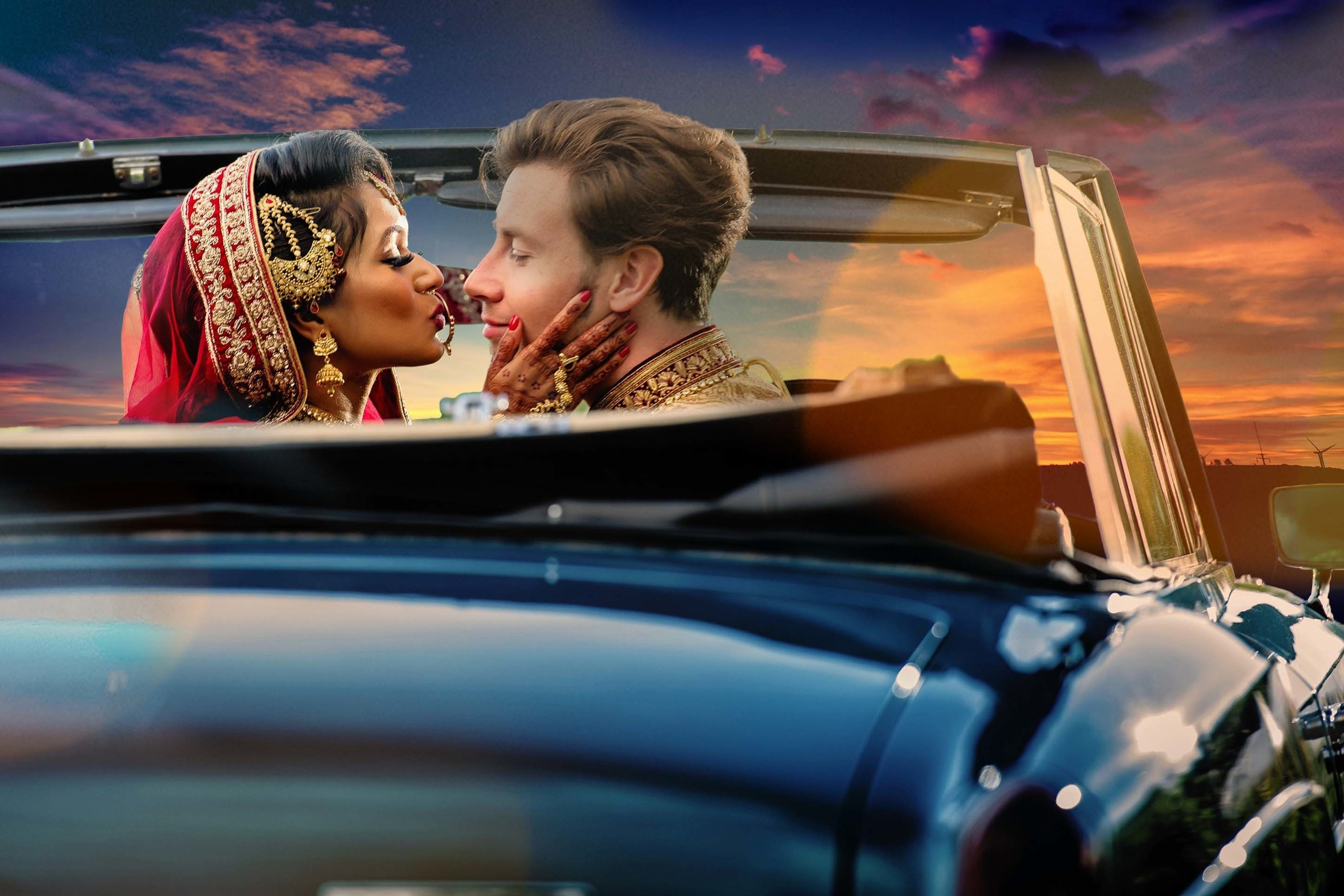 Bride in traditional attire kissing groom in a vintage convertible during sunset Guildford, UK