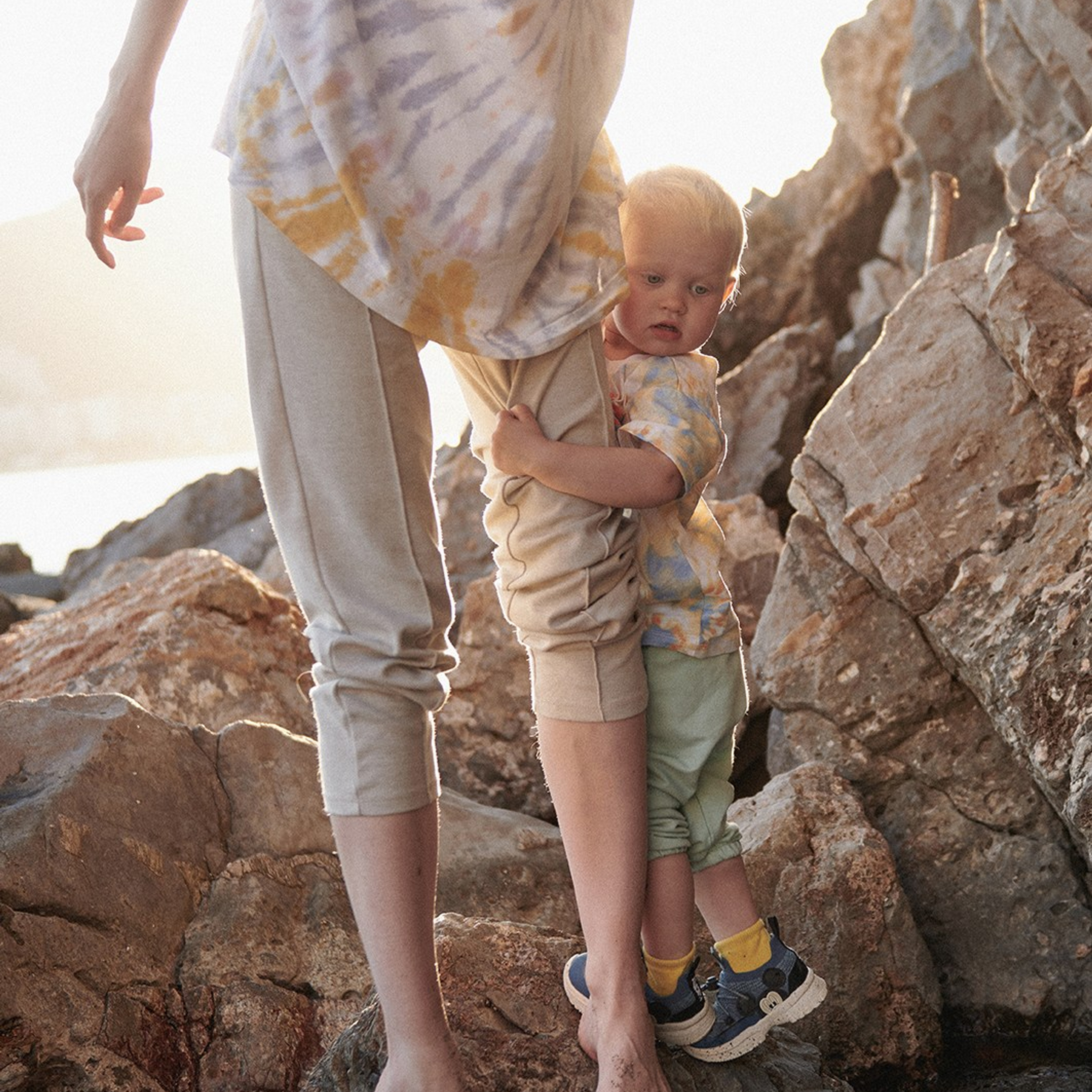 Lifestyle kid’s photoshoot hugging her mother in natural tender light by the sea