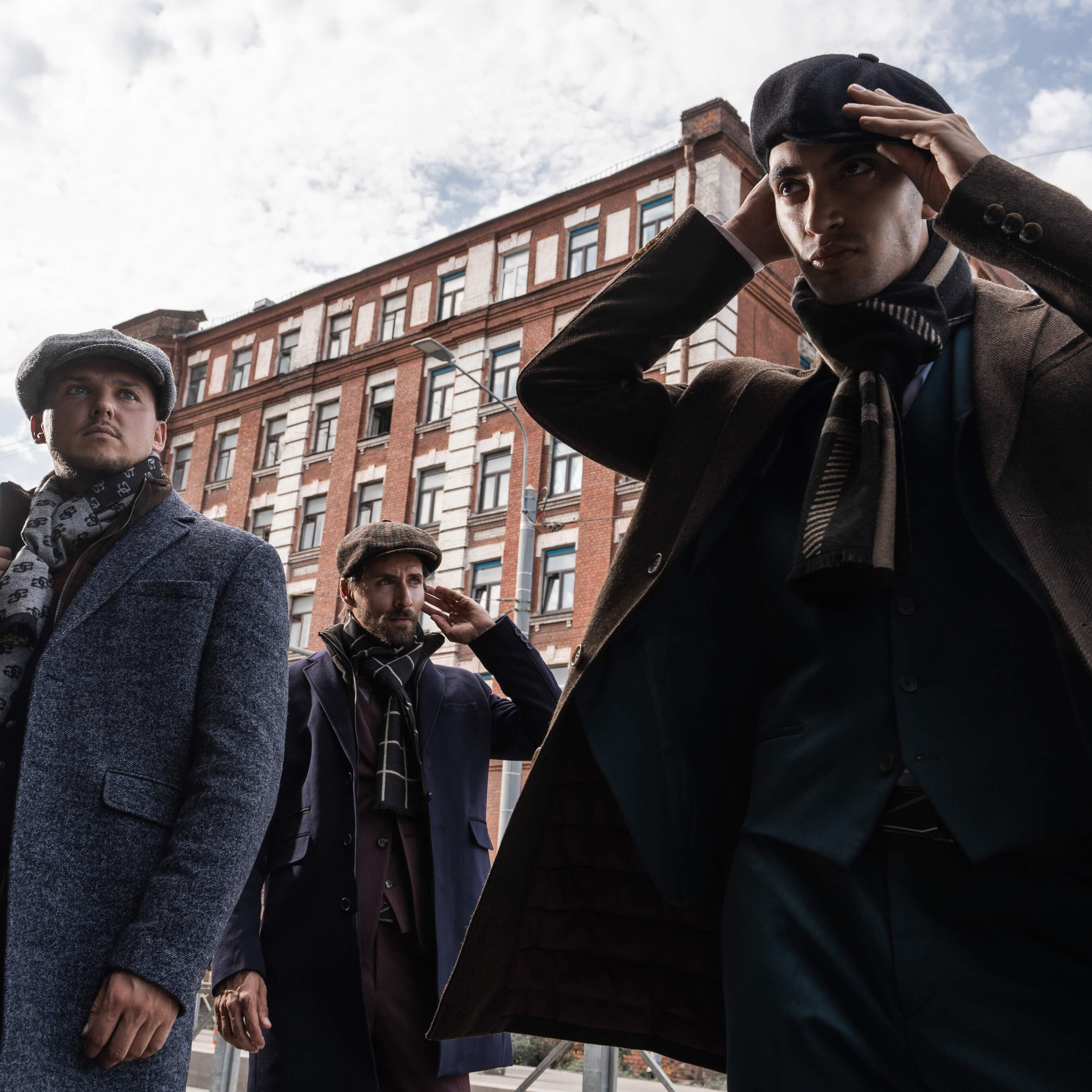 Dynamic shot of a group of men in stylish overcoats and hats, portraying confidence and timeless fashion on a city street, as captured by a skilled photographer from Italy
