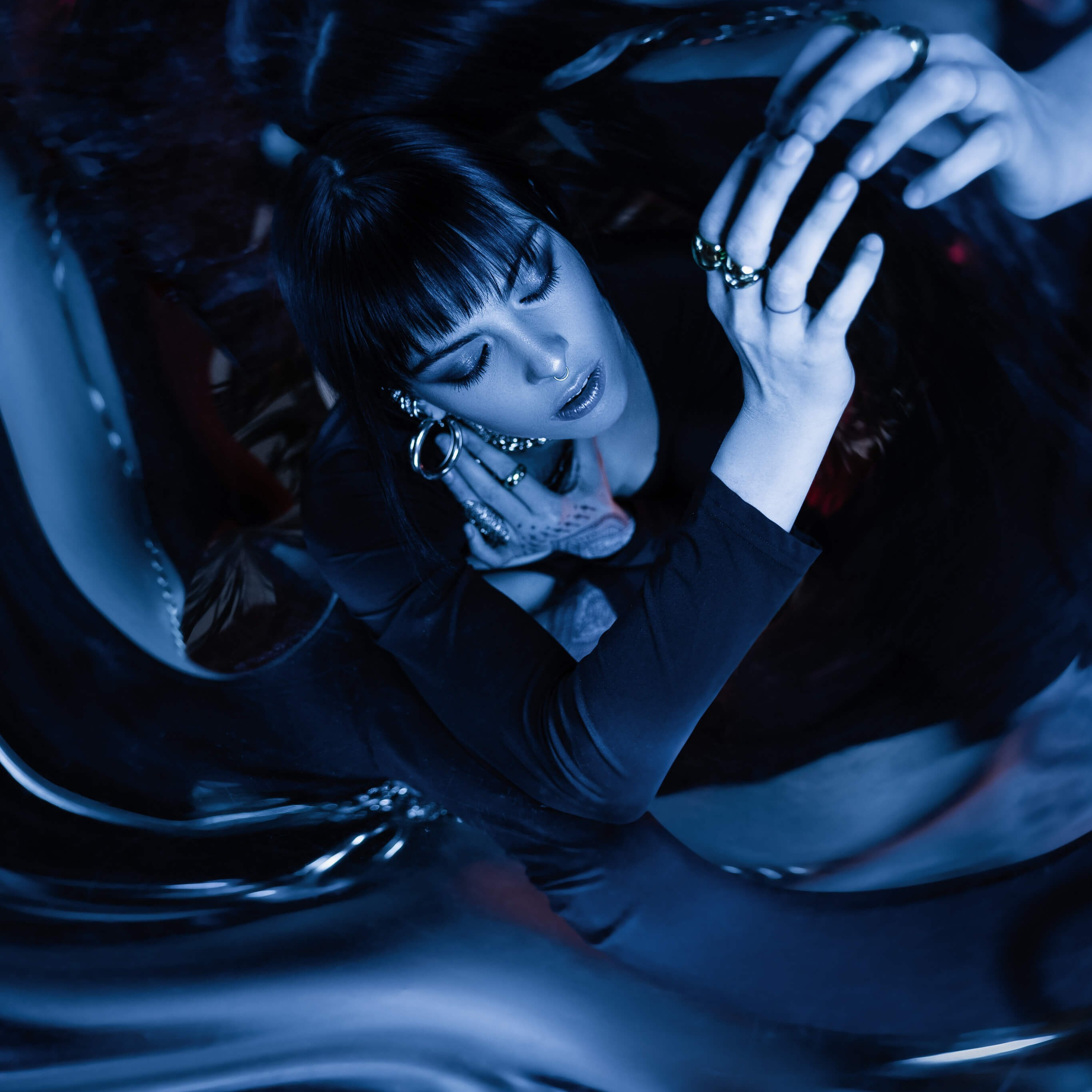 Photographer's creative composition with a mirror effect, showcasing a woman adorned in elegant jewelry, her image reflected and multiplied in a serene blue ambiance