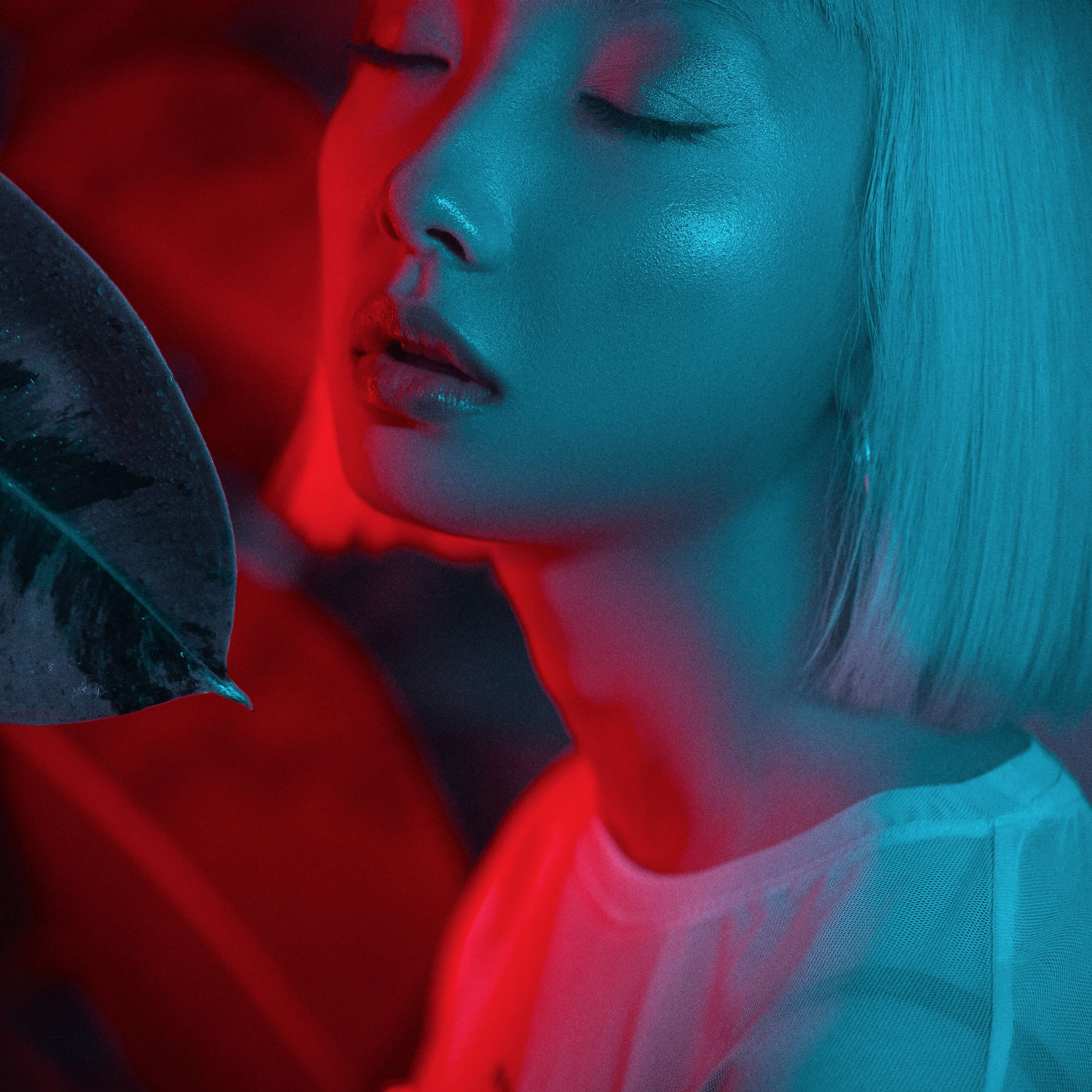 An artistic portrayal by a photographer of a woman's profile, her face painted with vibrant red and blue shadows that blend into a striking and emotive composition