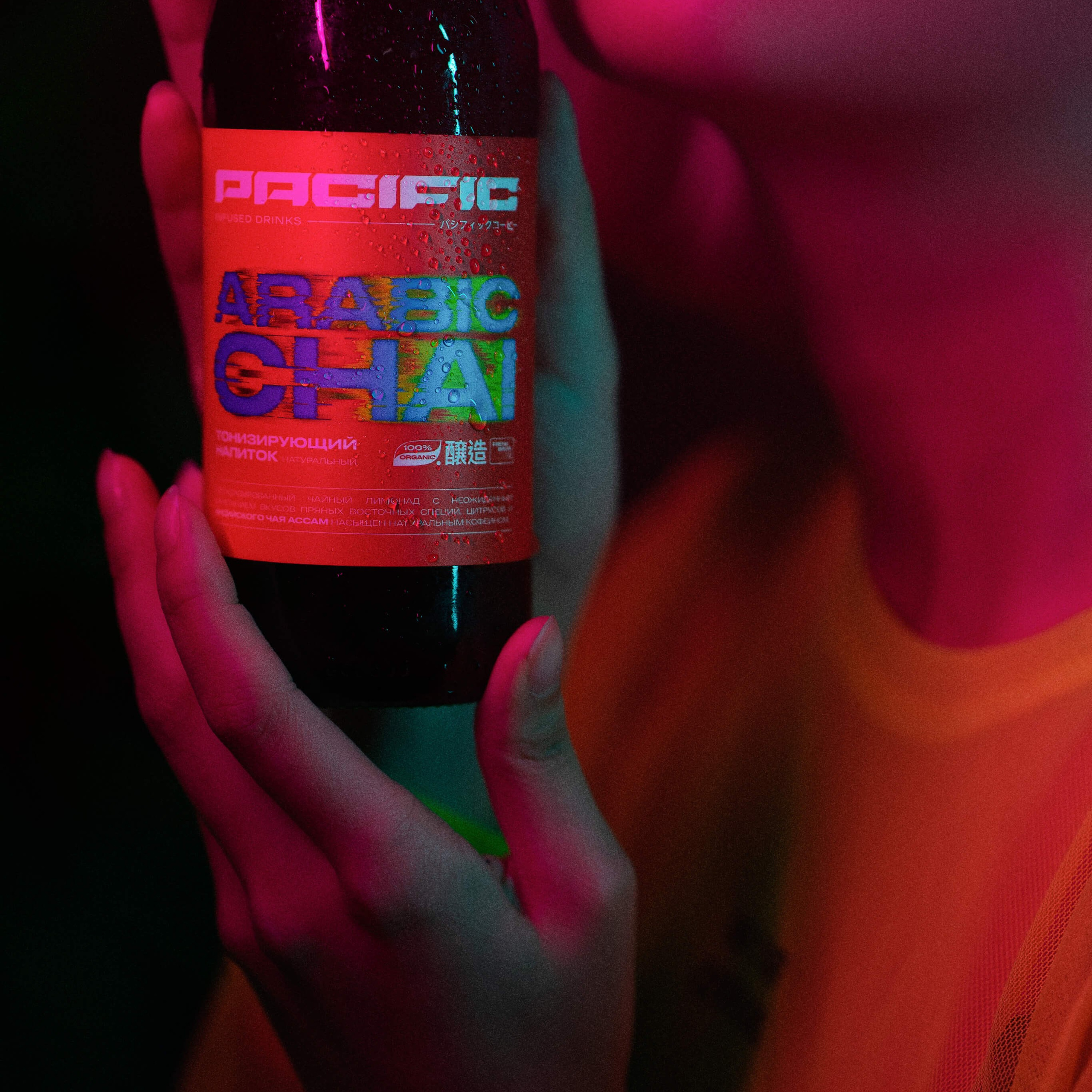 A close-up image capturing the sensual curves of lips slightly parted, with a hand holding a bottle of 'Arabic Teai' near the face, all under a mesmerizing neon light that sets a mysterious and alluring mood