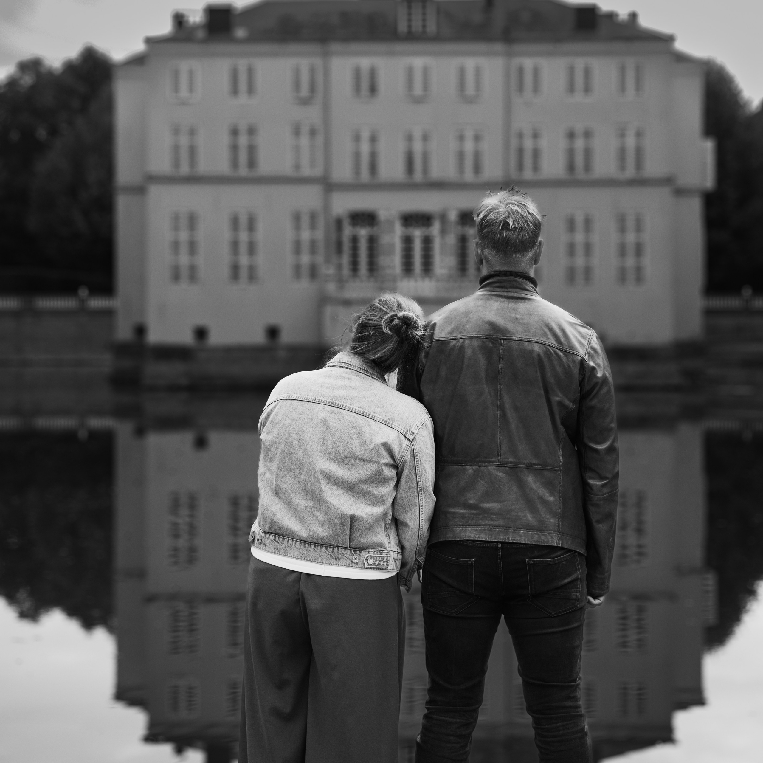 Koppel staat naast elkaar en kijkt naar kasteel met de rug naar de camera tijdens romantische fotoshoot - Kapture Fotografie