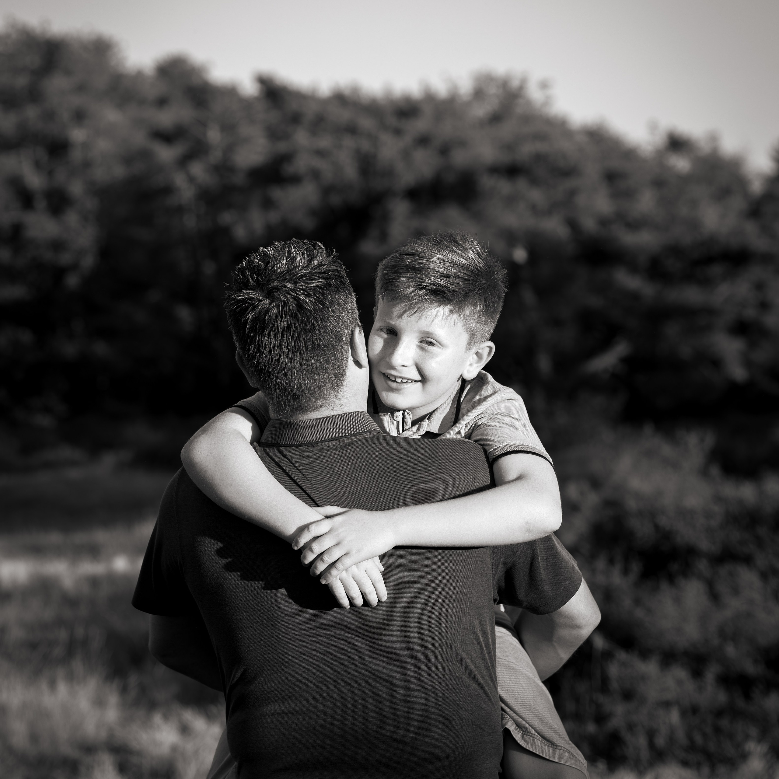 Vader en zoon delen een warme knuffel tijdens lifestyle fotosessie - Kapture Fotografie