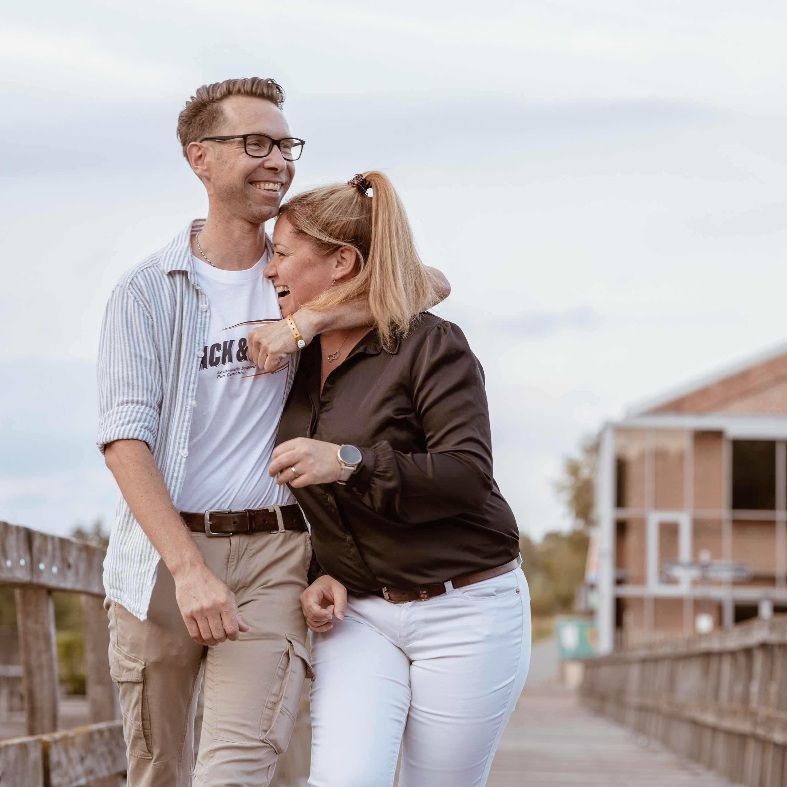 Broer en zus wandelen lachend over een brug tijdens spontane buitenfotoshoot - Kapture Fotografie
