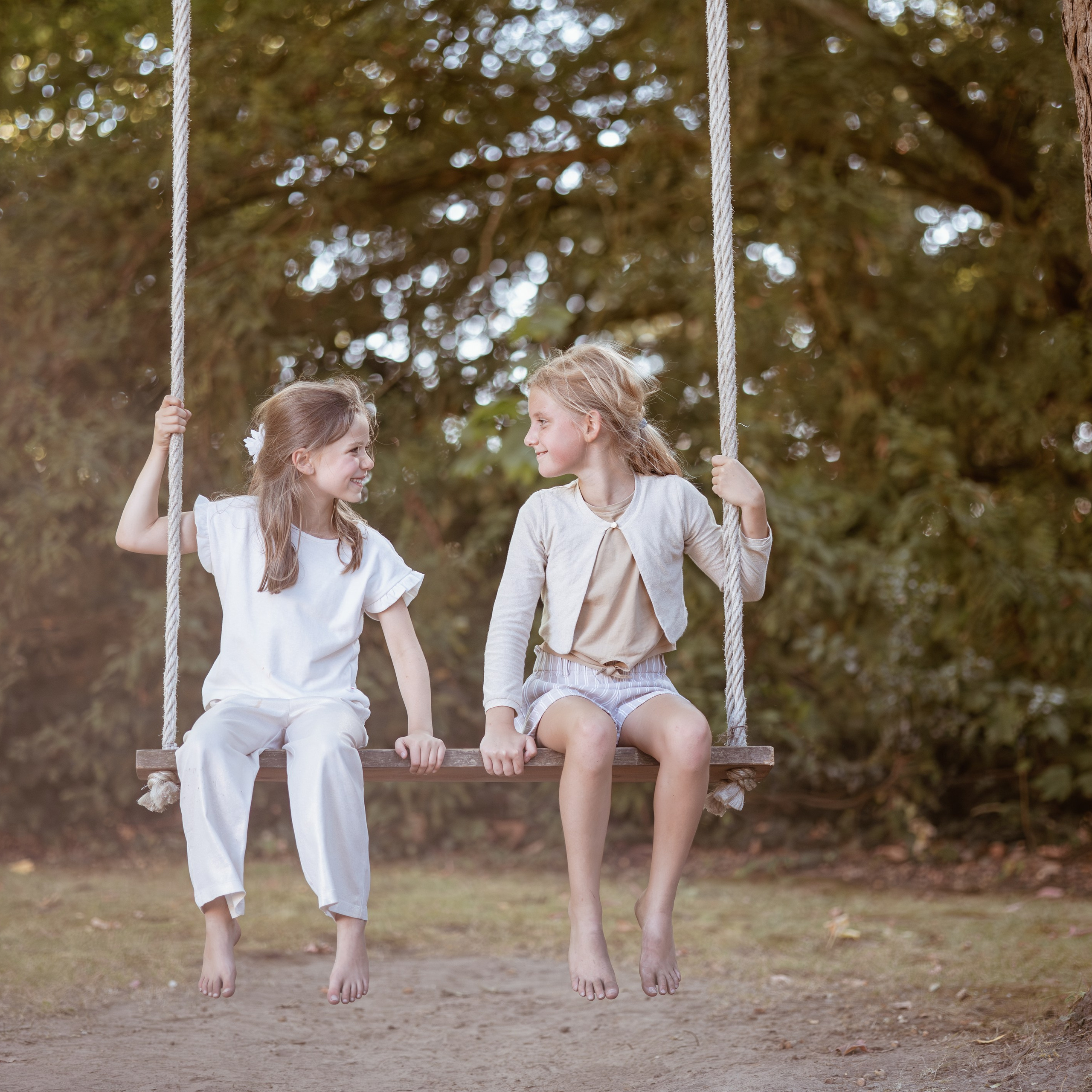 Twee meisjes op een schommel tijdens zonsondergang vastgelegd in warm natuurlijk licht - Kapture Fotografie