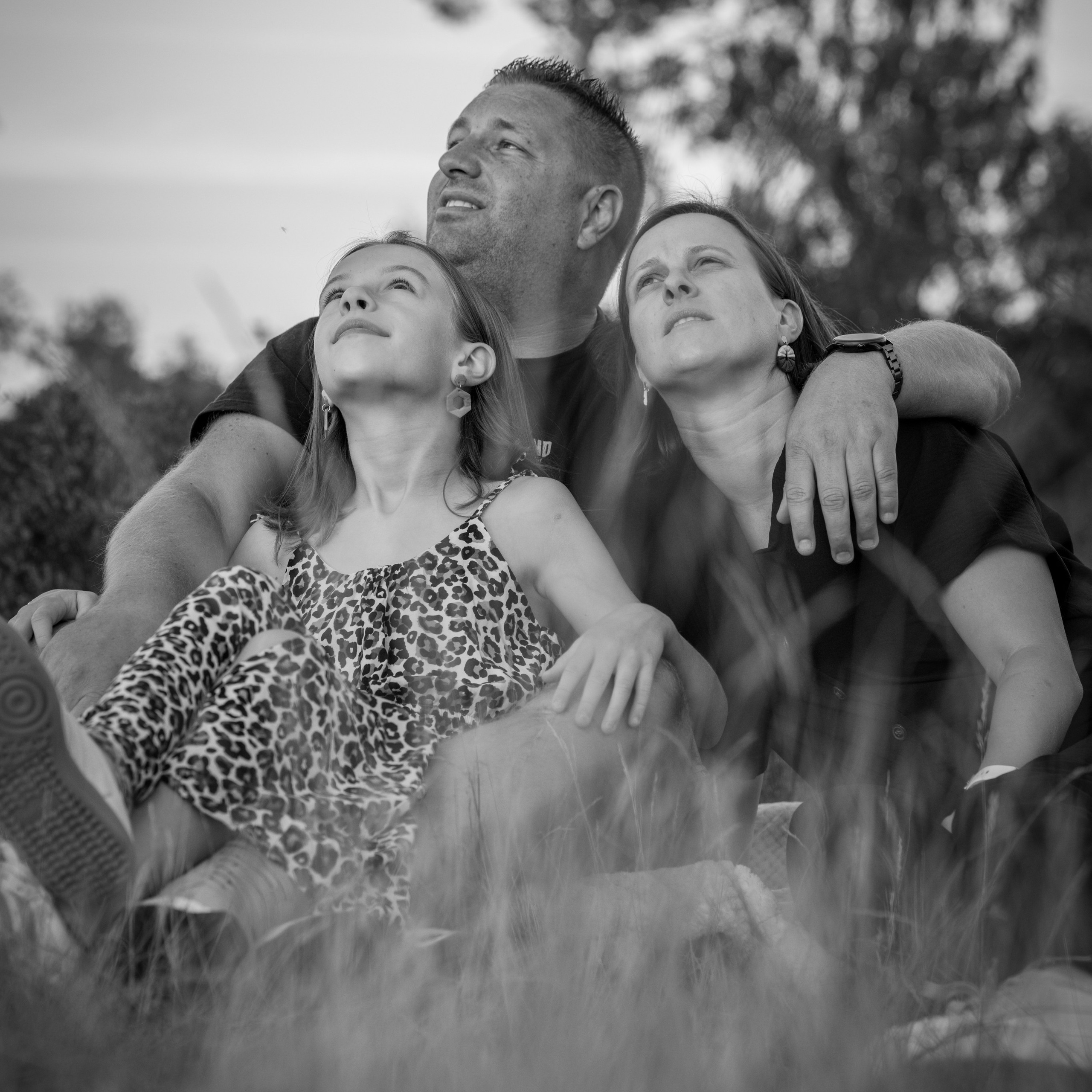 Zwart-wit familiefoto van gezin zittend in het gras tijdens spontane buitenfotoshoot - Kapture Fotografie