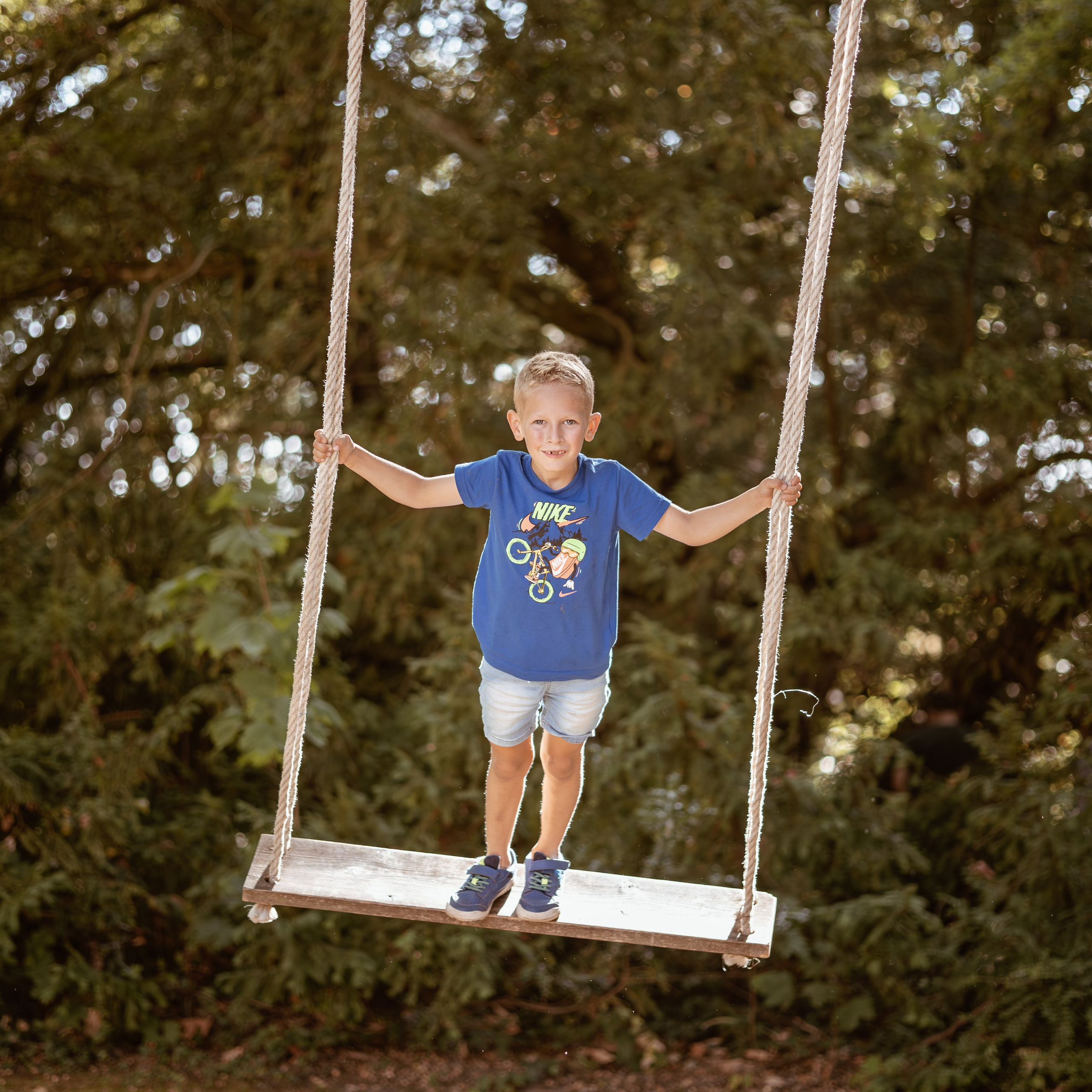 Kind schommelt in de neergaande zon tijdens warme en speelse buitenfotoshoot - Kapture Fotografie