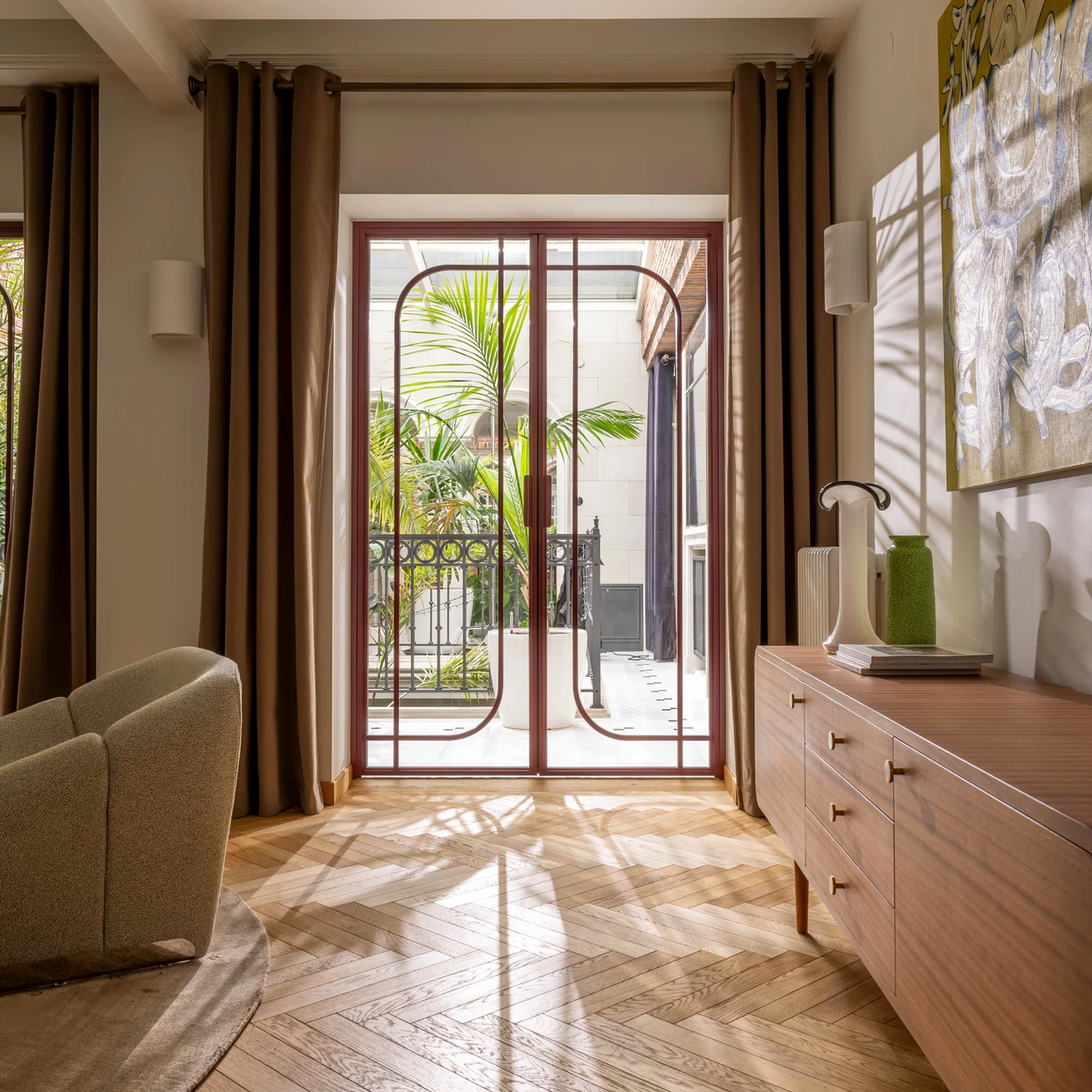 Nowoczesne studio do zdjęć – designerski fotel, drewniana komoda i kolorowy obraz, idealne tło do portretów.